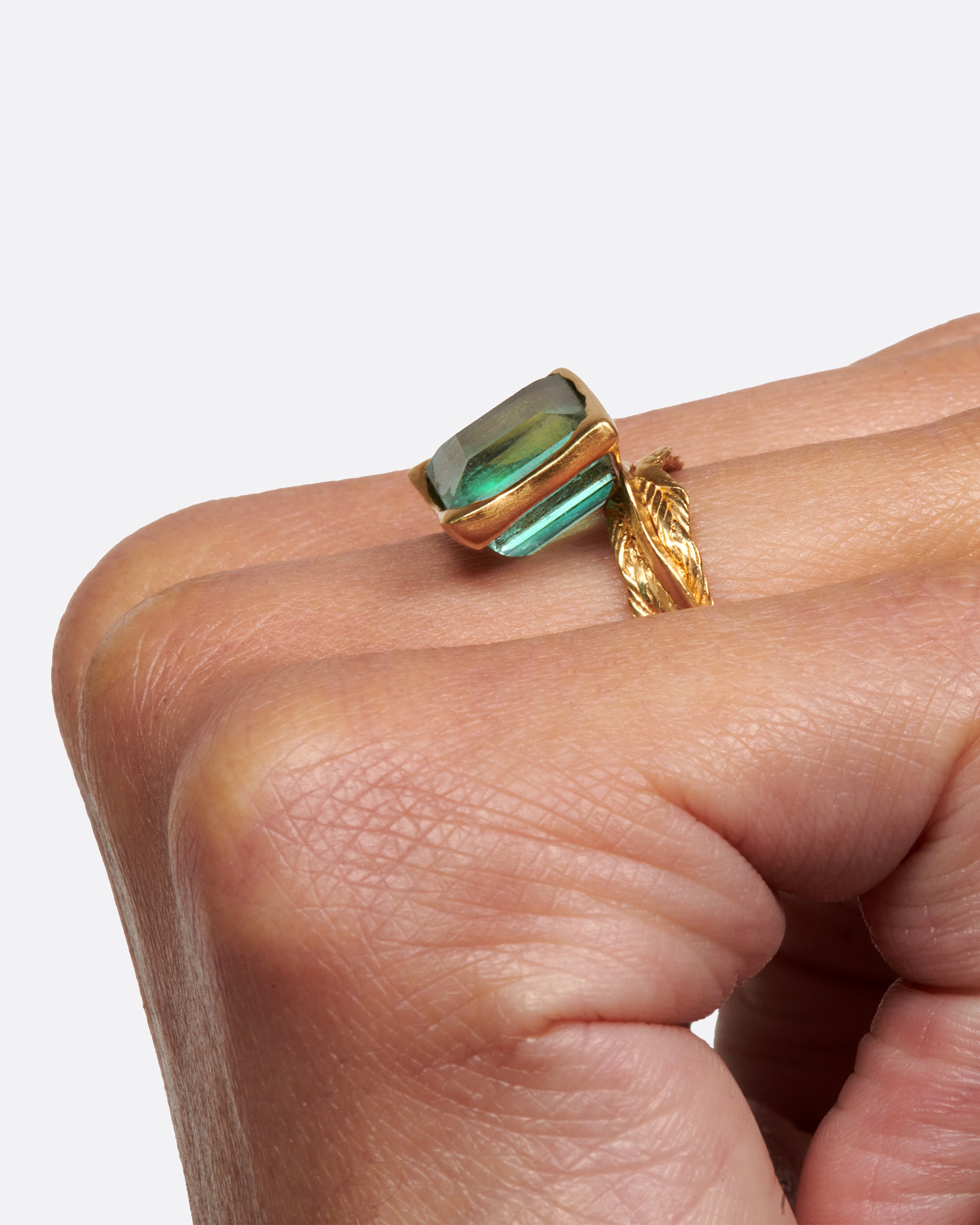 A gold braided band with a pale green square tourmaline.