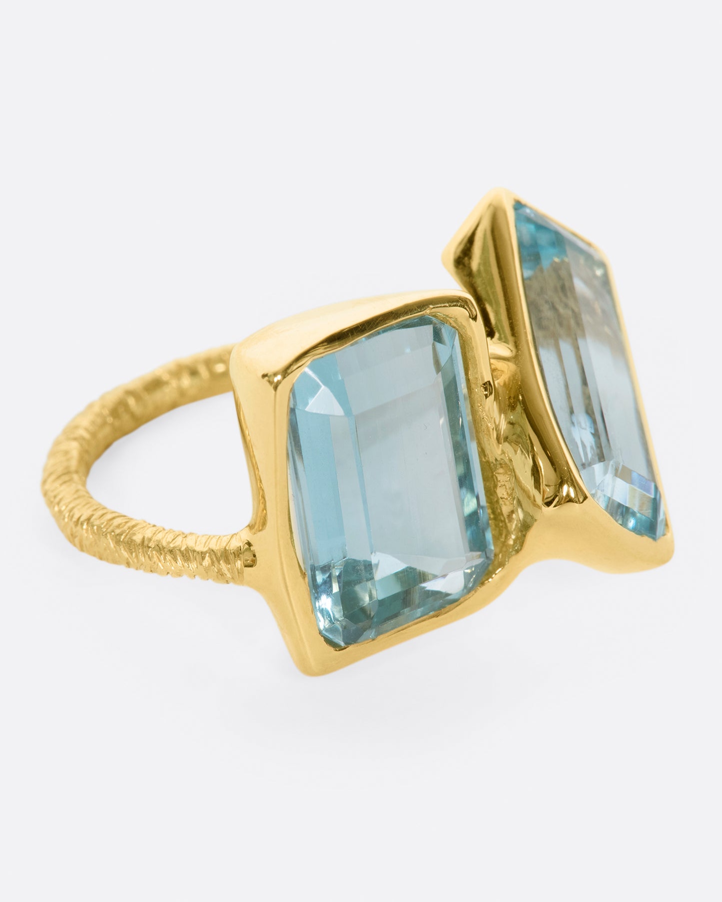 A yellow gold ring featuring two large emerald cut aquamarines set slightly askew