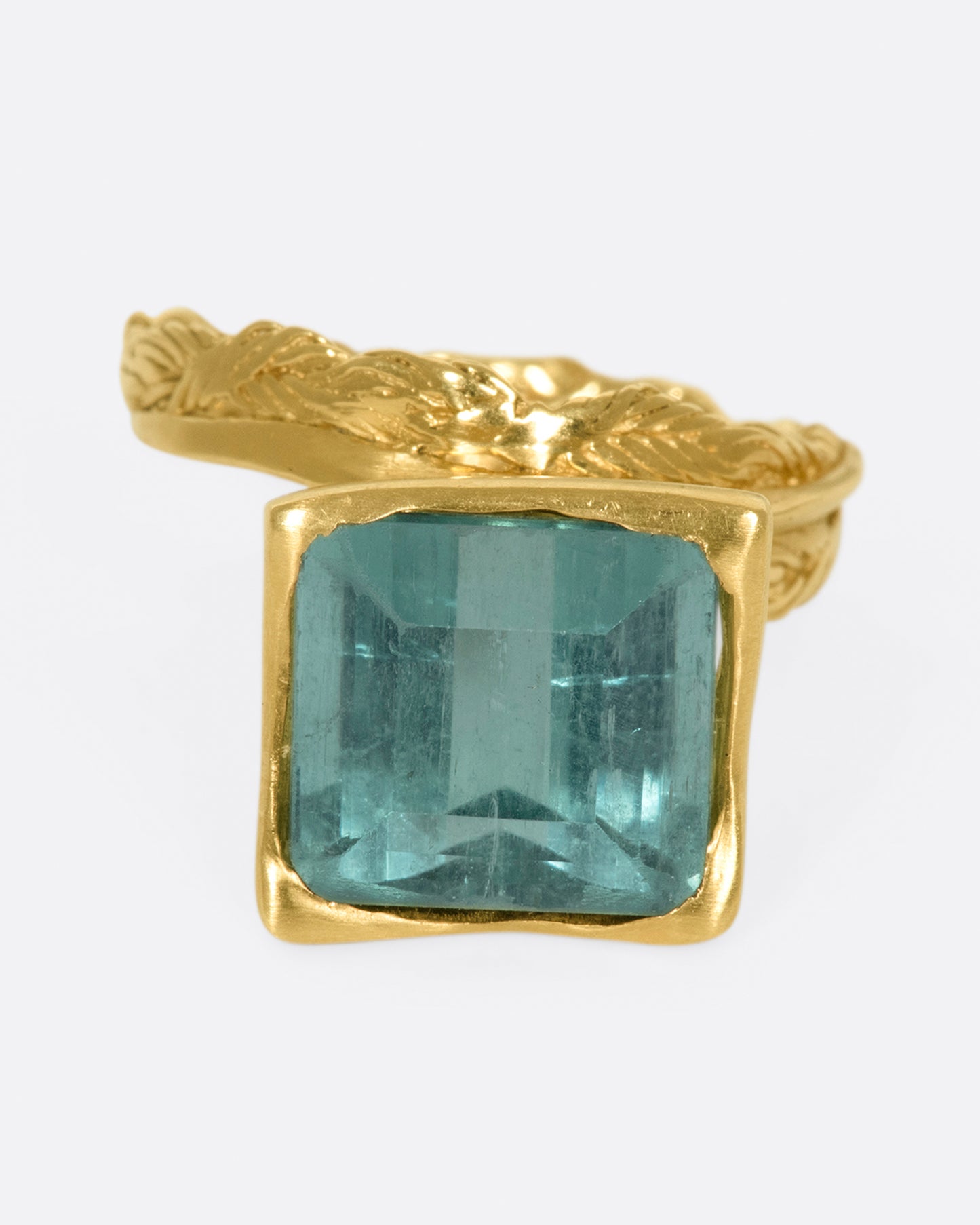 A gold braided band with a pale green square tourmaline.