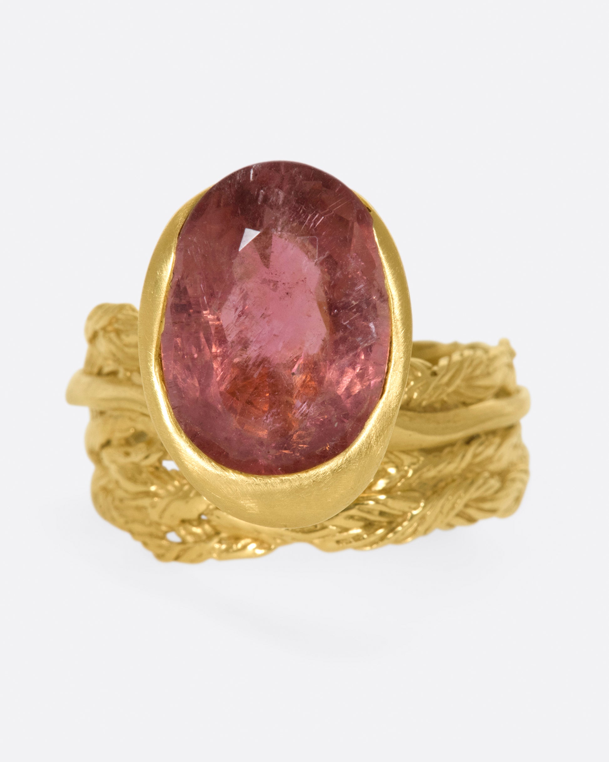 A gold braided band with an oval shaped rose tourmaline.