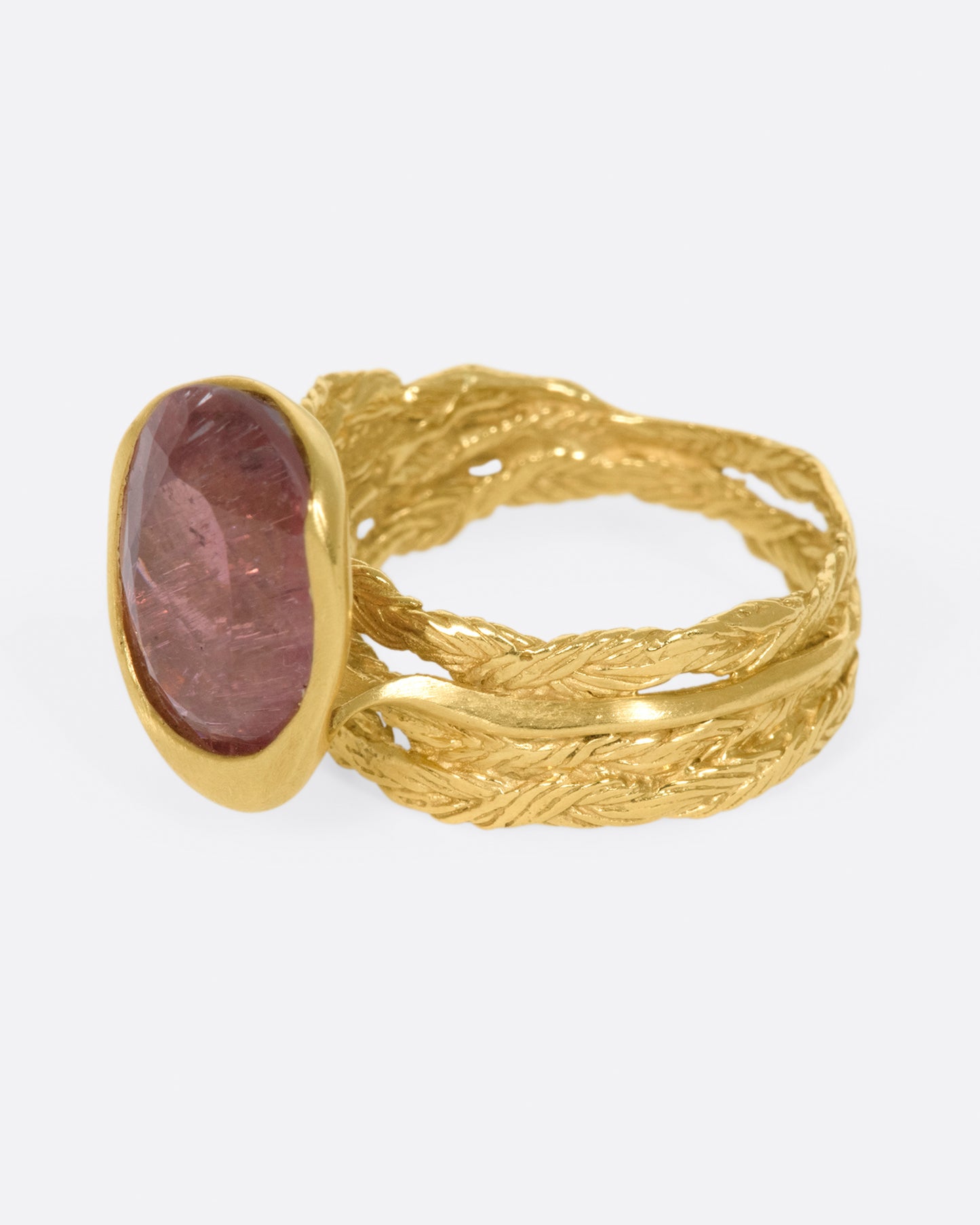 A gold braided band with an oval shaped rose tourmaline.