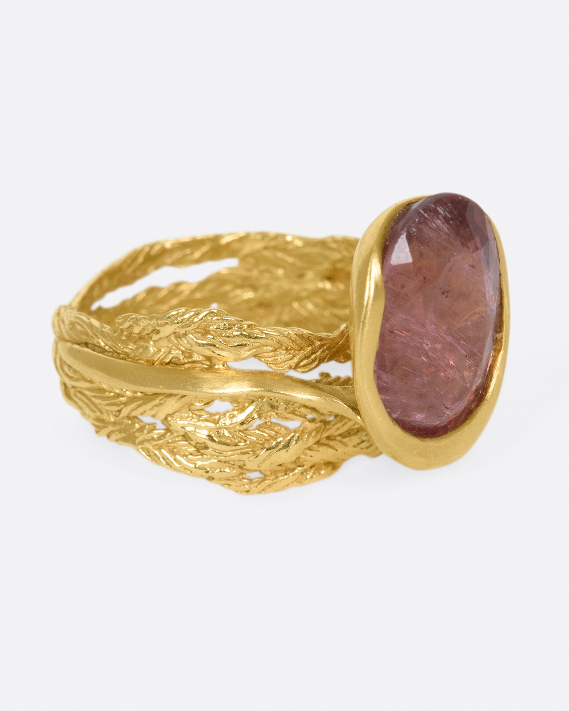 A gold braided band with an oval shaped rose tourmaline.