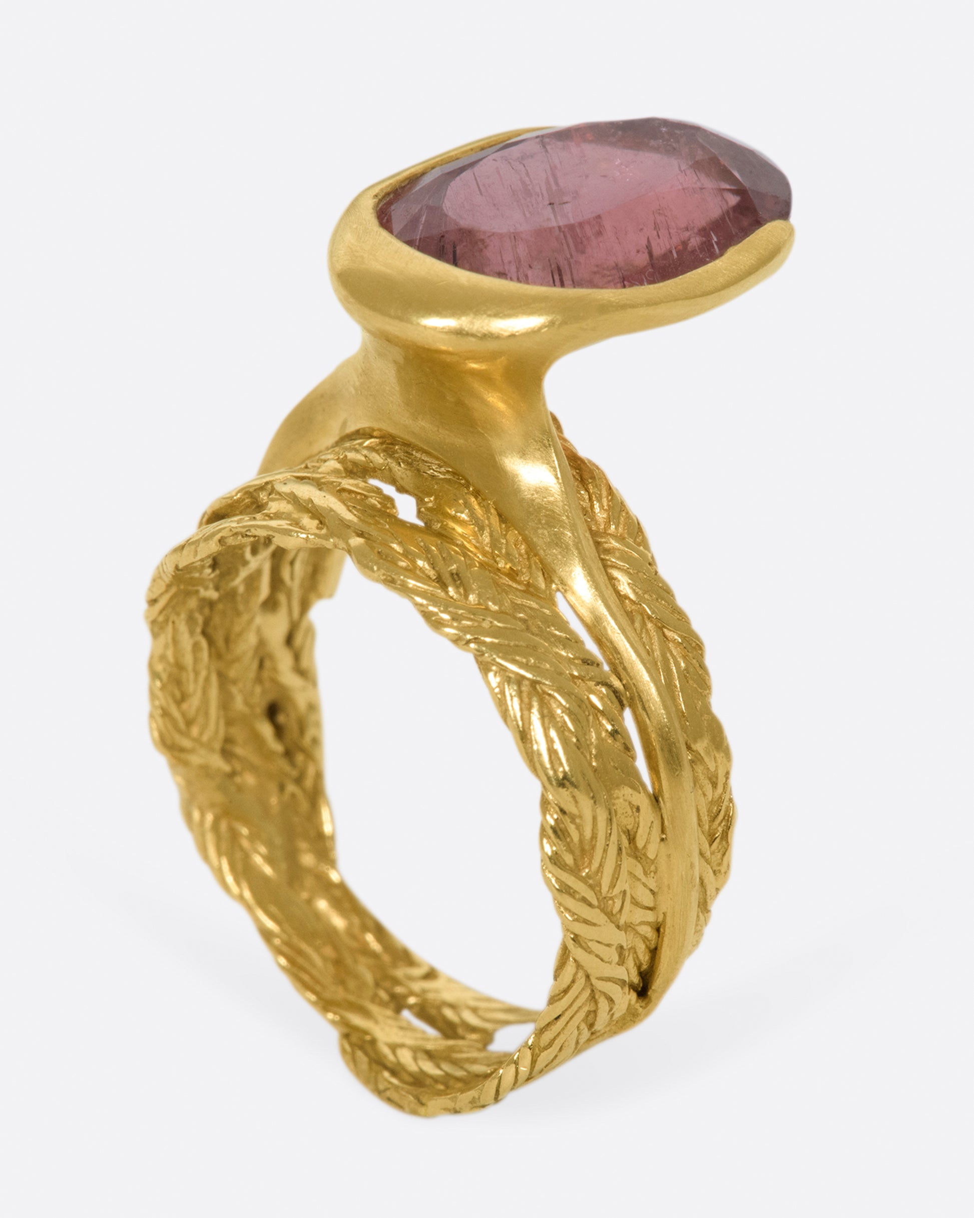 A gold braided band with an oval shaped rose tourmaline.