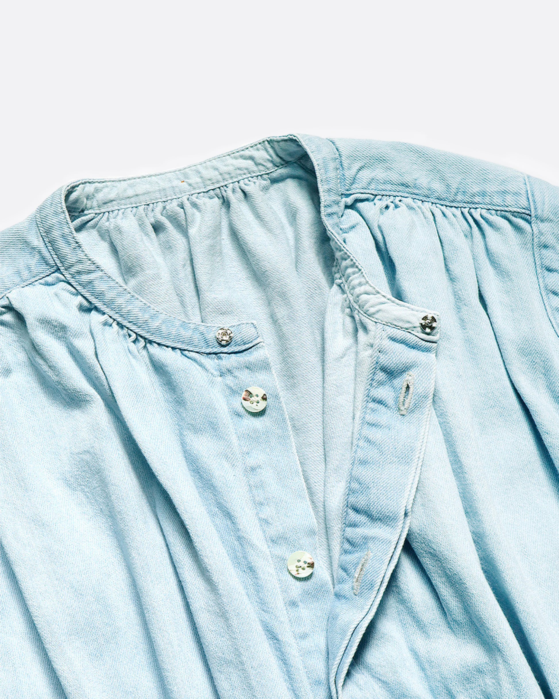 Sleeveless chambray jumpsuit with gathered waist, ruched bust and wide legs. Close up view of hidden front button closure.