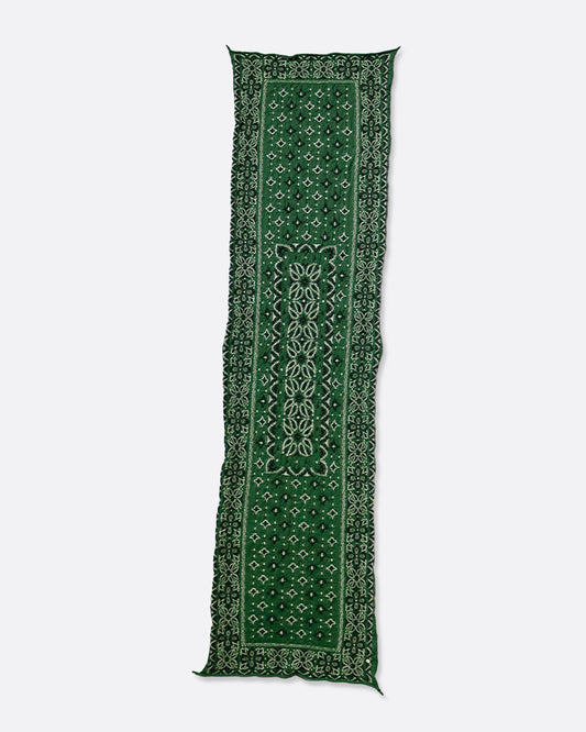 A green compressed wool scarf with a classic bandana pattern, shown lying flat.