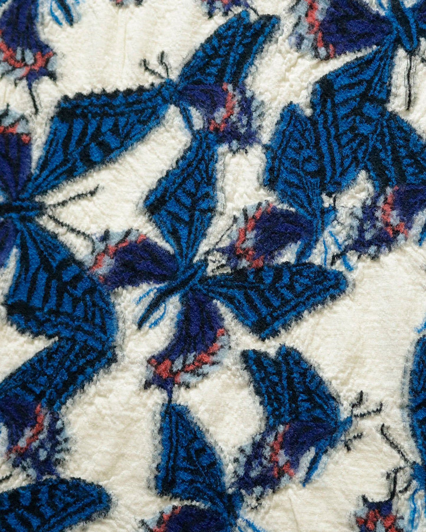 A close up of a white compressed wool scarf with blue butterflies all over it.
