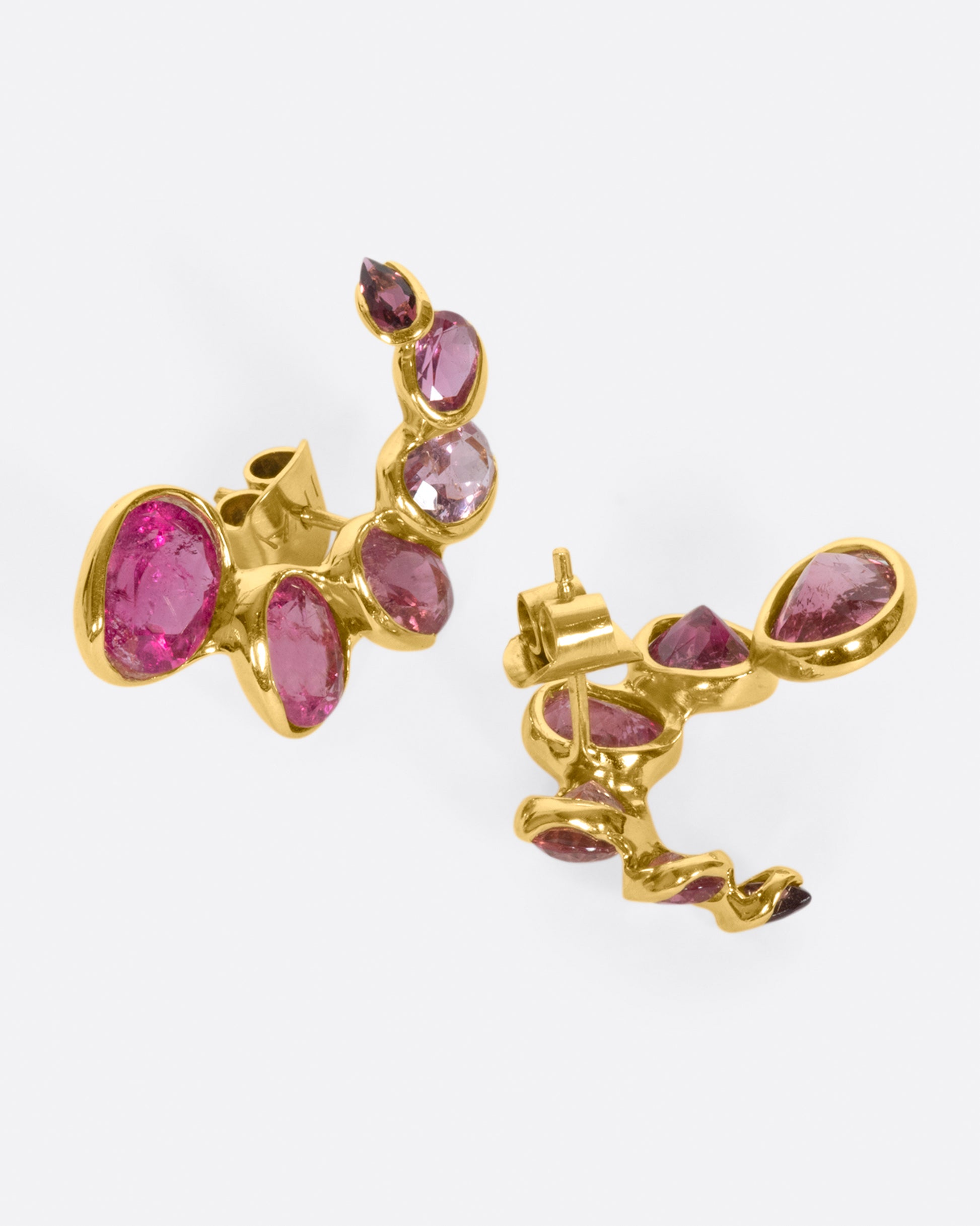 A pair of curved earrings with ombré pink tourmalines, shown from the side.