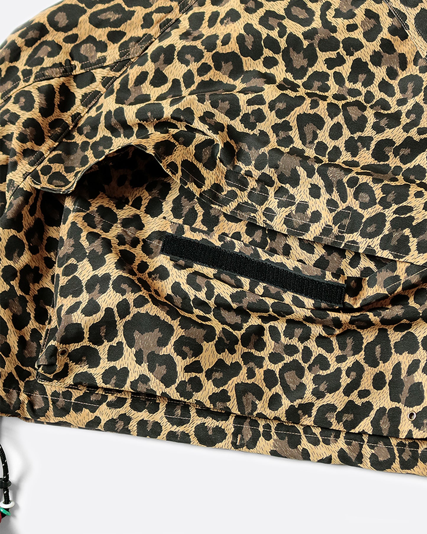 Cropped leopard rain jacket with hood and two front pockets. View from the back of back large pocket open.