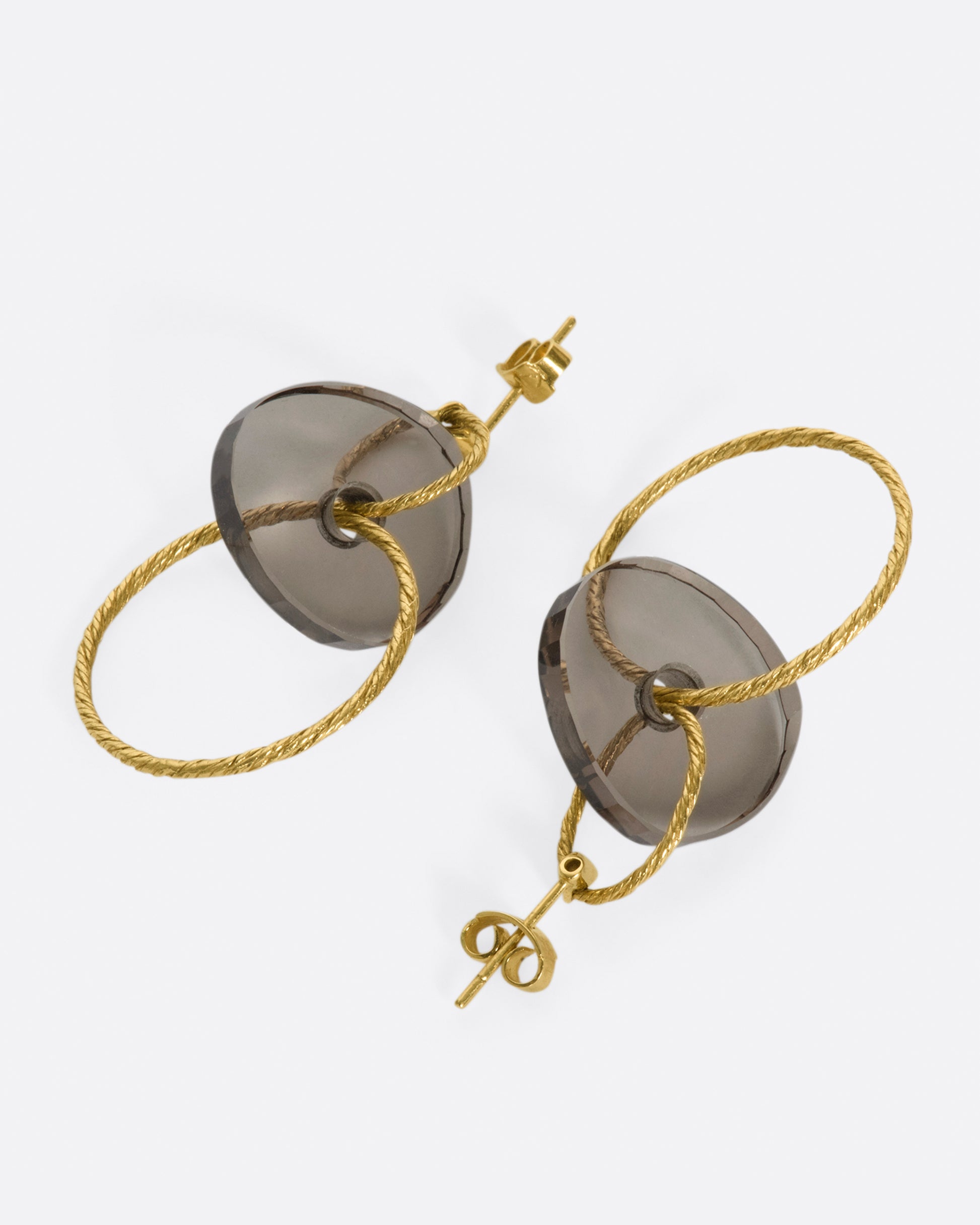 A pair of yellow gold stud earrings with two circular drops that are connected by smokey quartz beads.