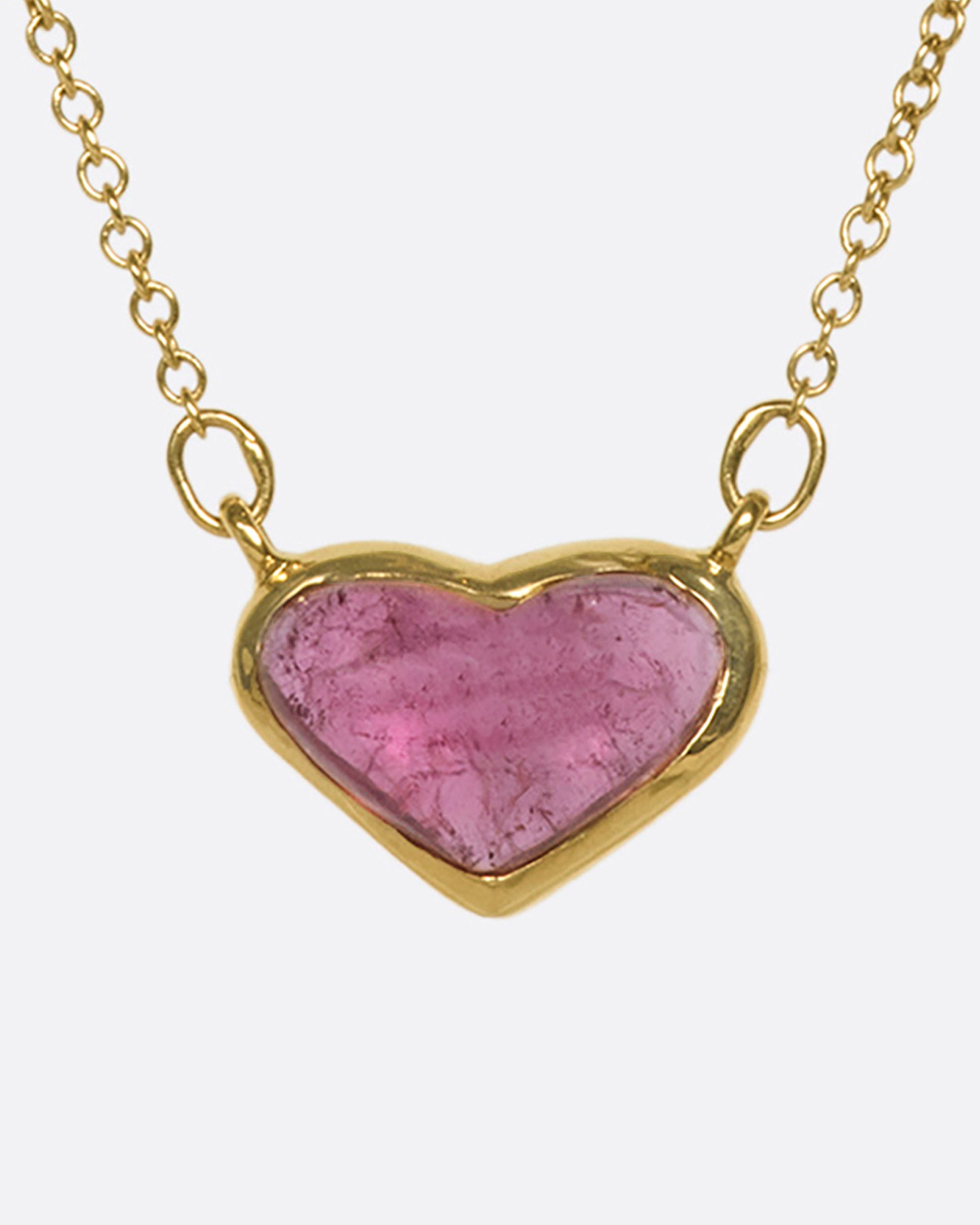 This 18k gold chain holds a unique watermelon rubellite heart encased in a gold bezel setting