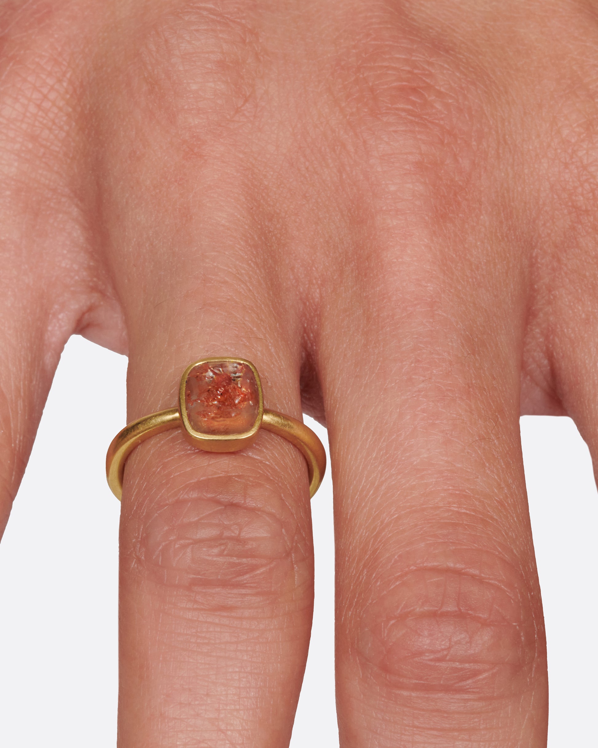 A cushion shaped, rusty-red diamond in one of Lola Brooks' signature bezel settings.