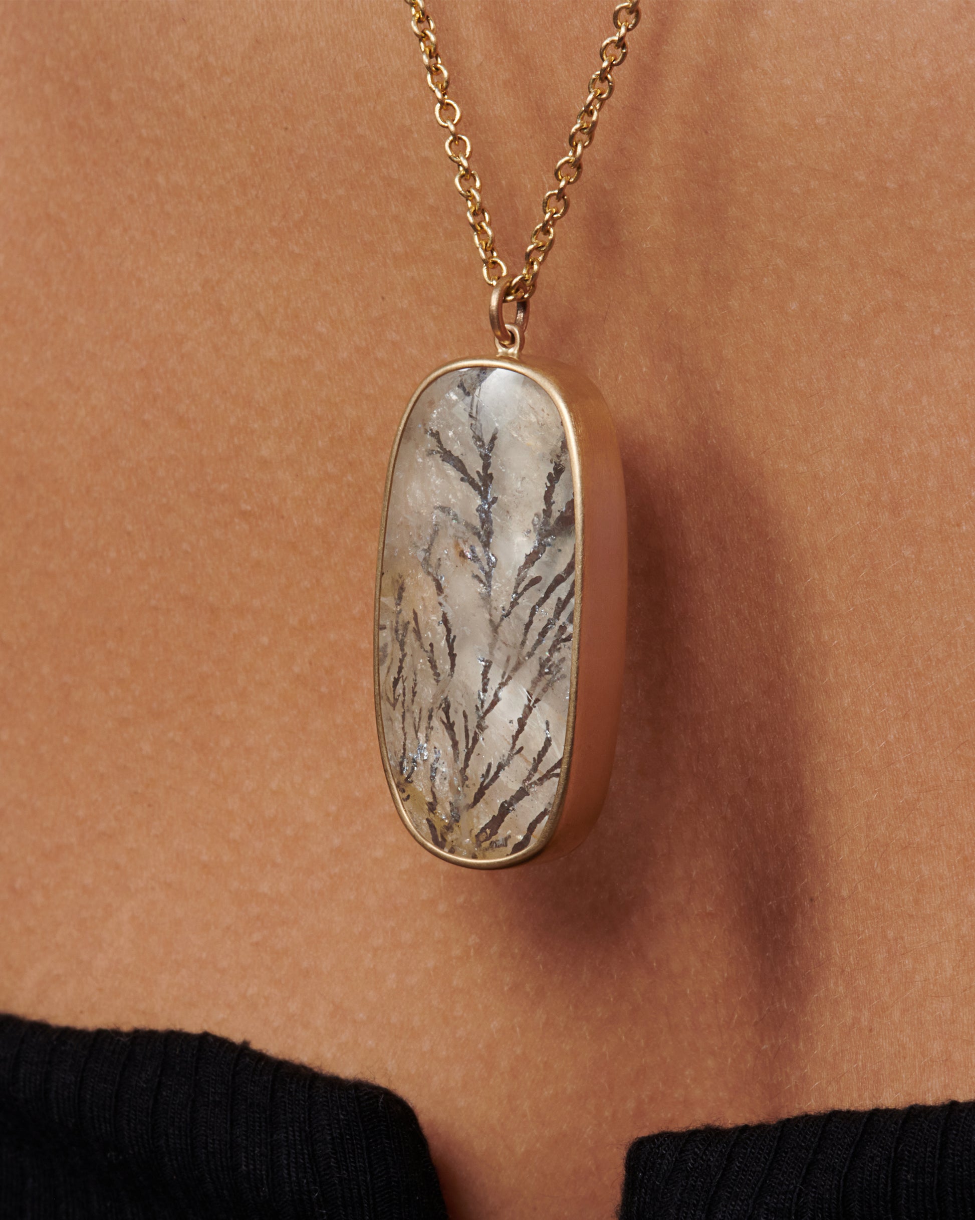 This oval dendritic quartz pendant has fern like iron strands growing throughout and a notable changing luster, known as chatoyance.