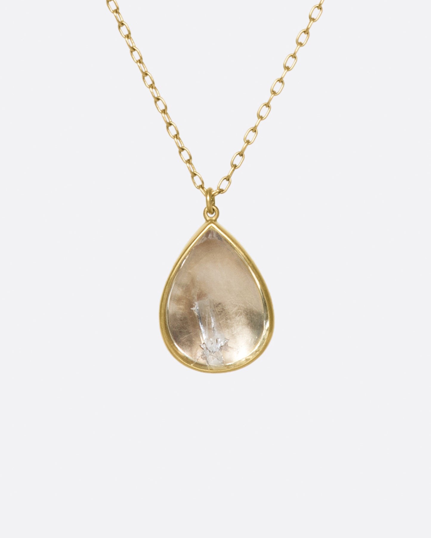 A gold necklace with a quartz crystal teardrop pendant.