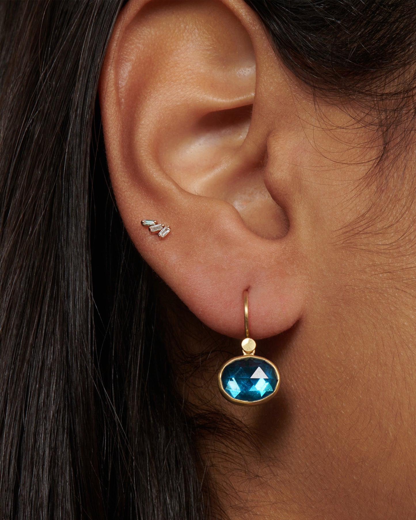 18k gold dangling earrings with oval London blue topaz drops. The rich blue topaz looks like sunlit water wrapped in a gold bezel setting.