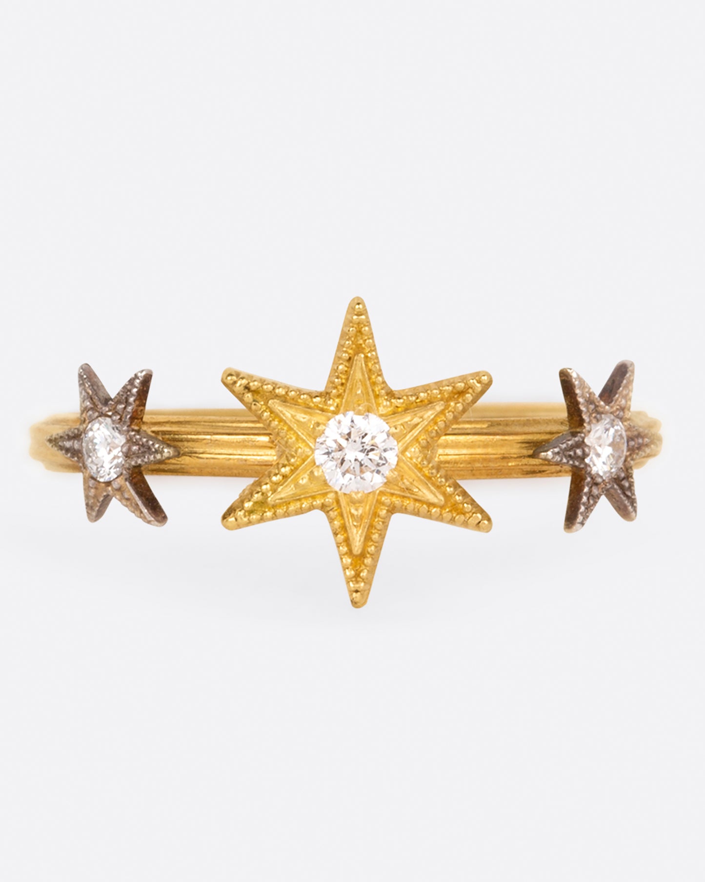 This ring features three millgrain stars; two platinum and one yellow gold, all dotted with diamonds.