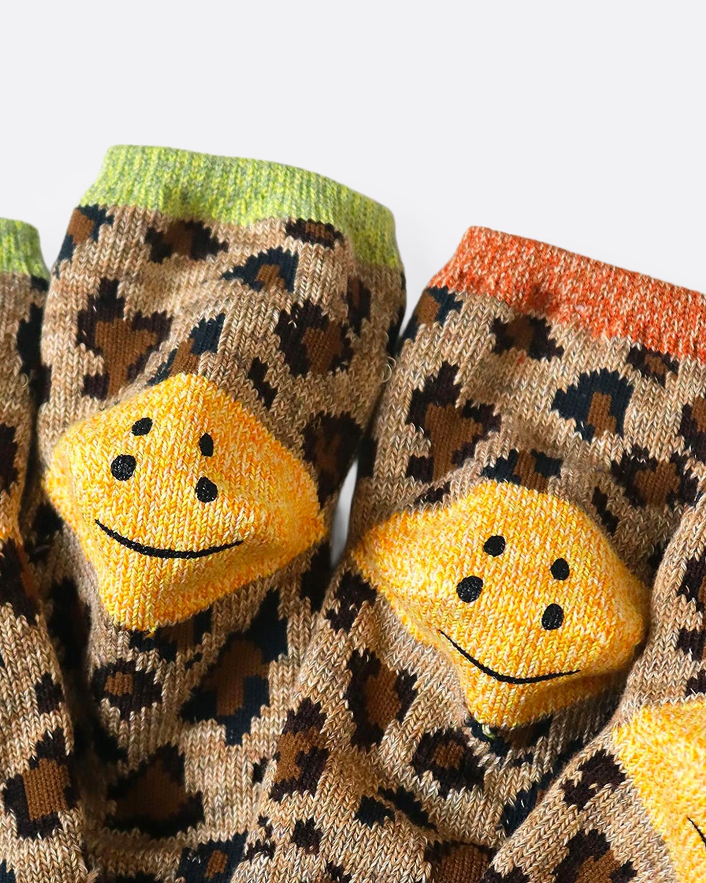 A close up of leopard print ankle socks with smiley faces on each heel. 