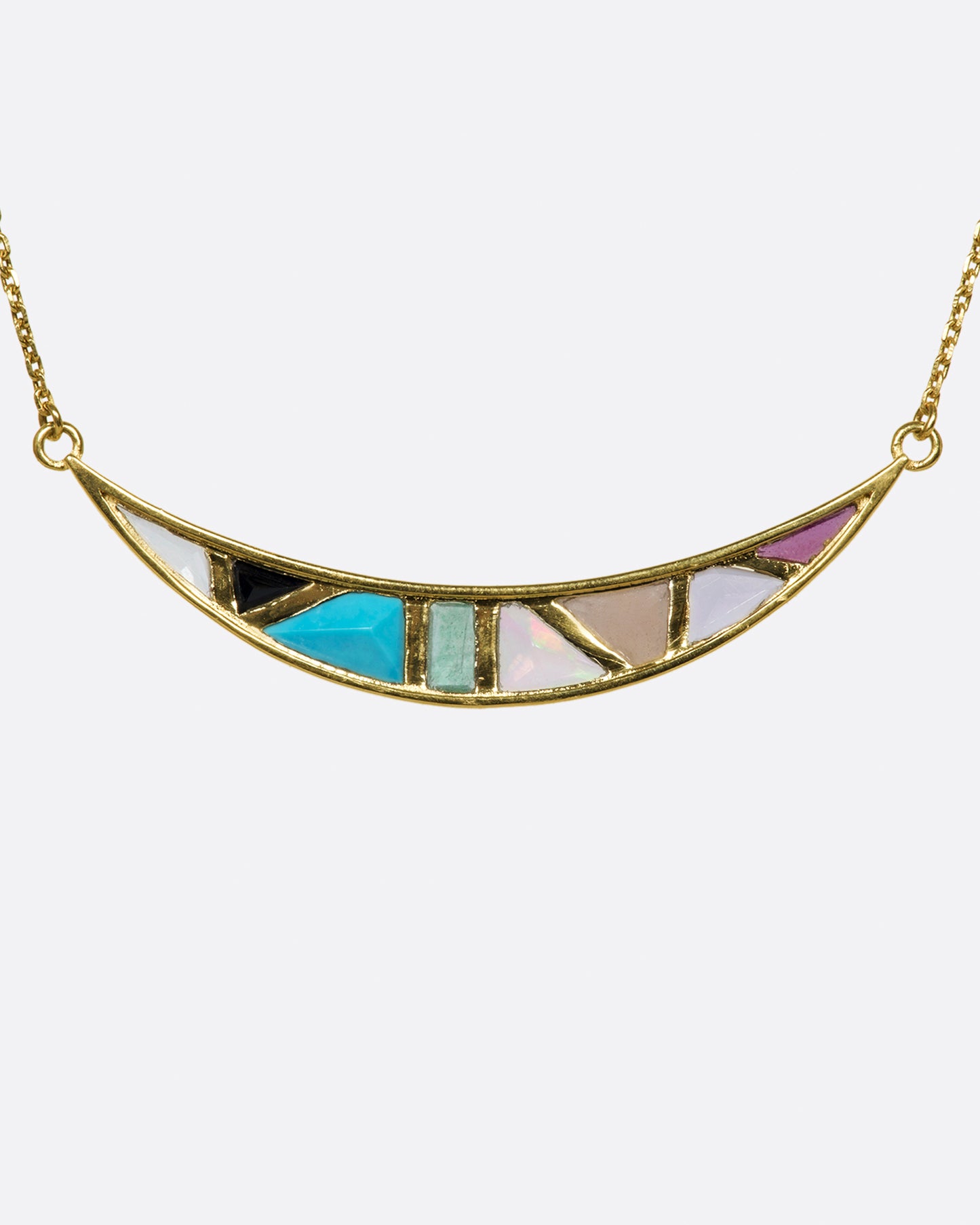 A crescent moon pendant necklace with a captivating mosaic of hand-cut stones.