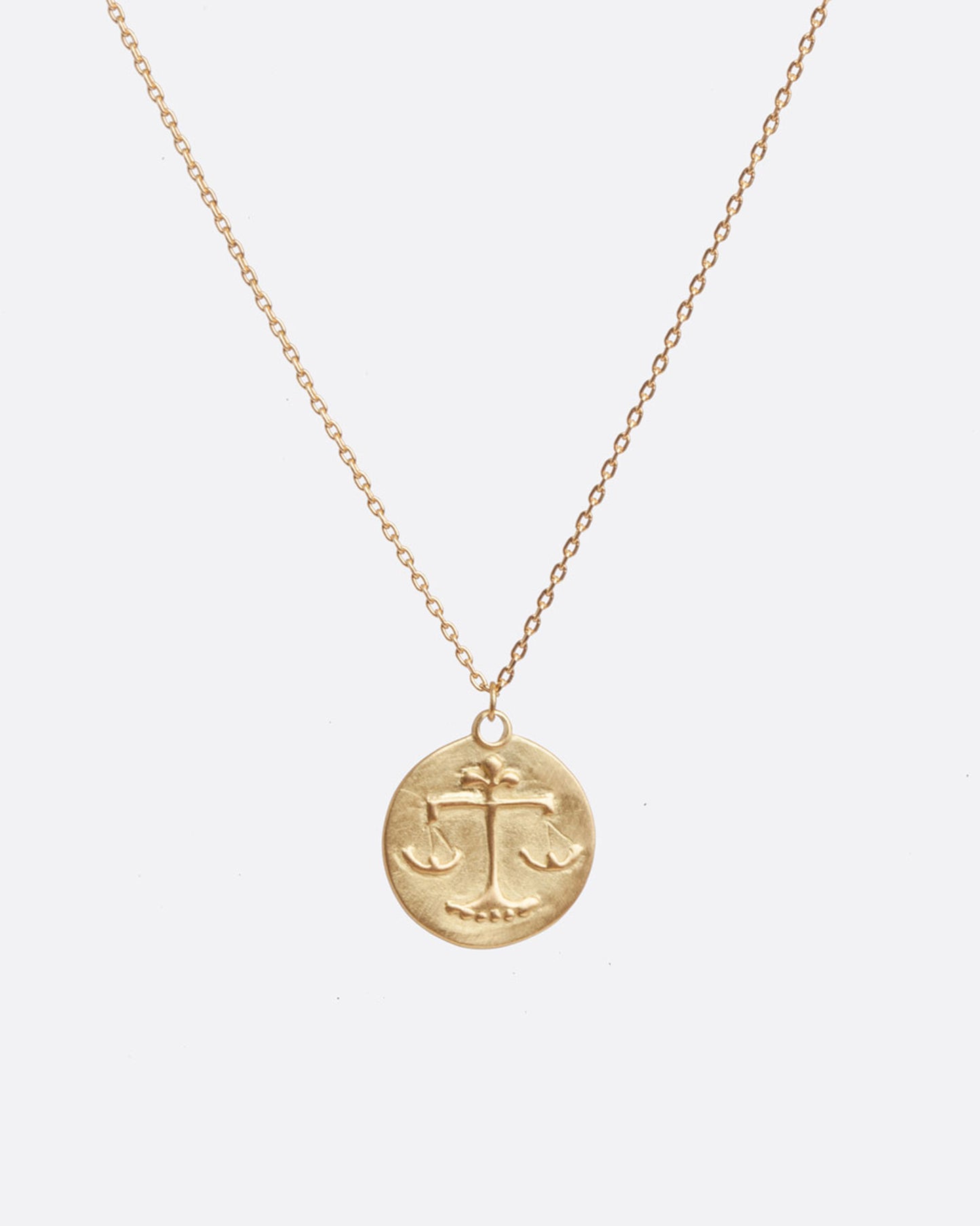 A yellow gold necklace with a round pendant with your choice of zodiac symbol.