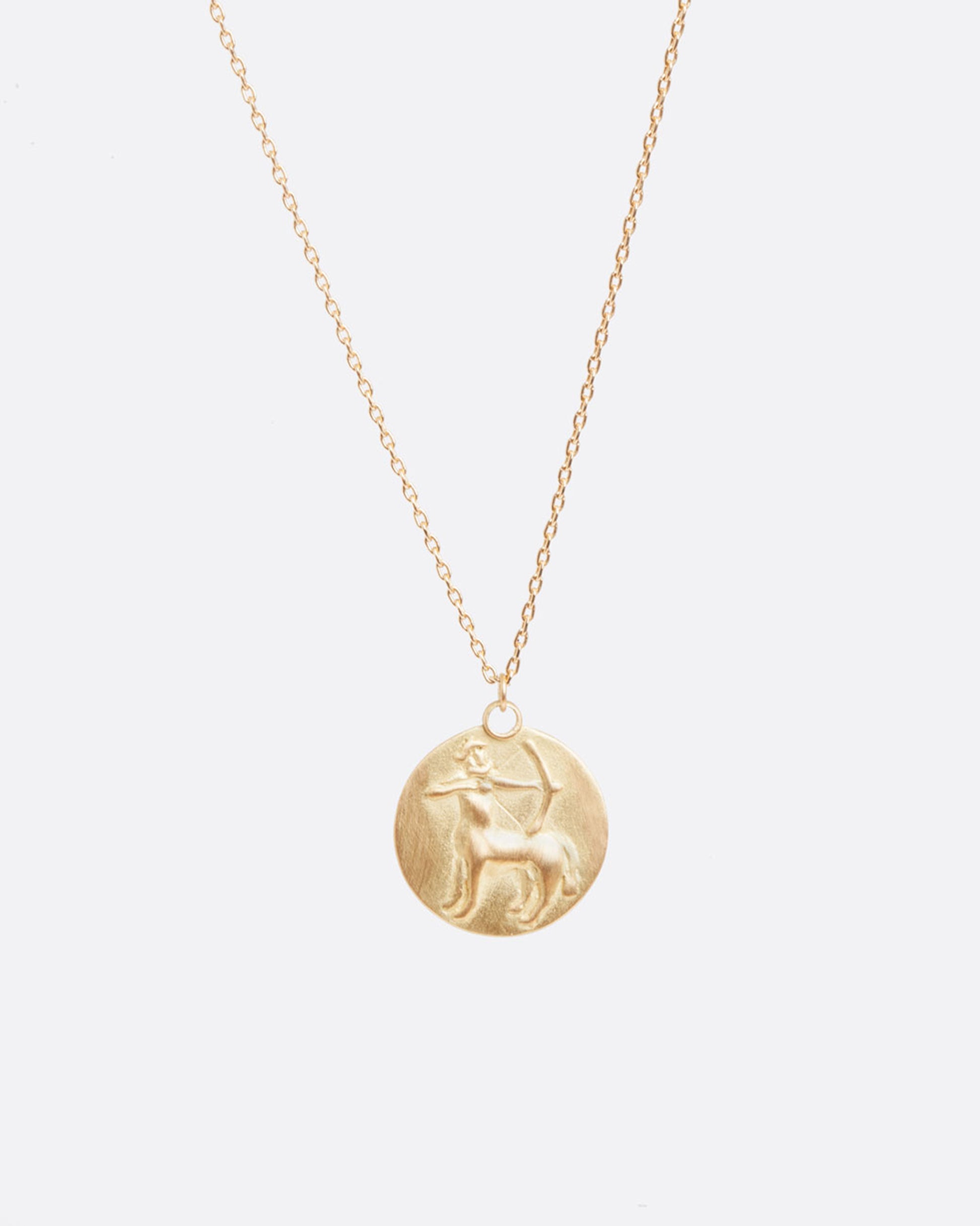 A yellow gold necklace with a round pendant with your choice of zodiac symbol.