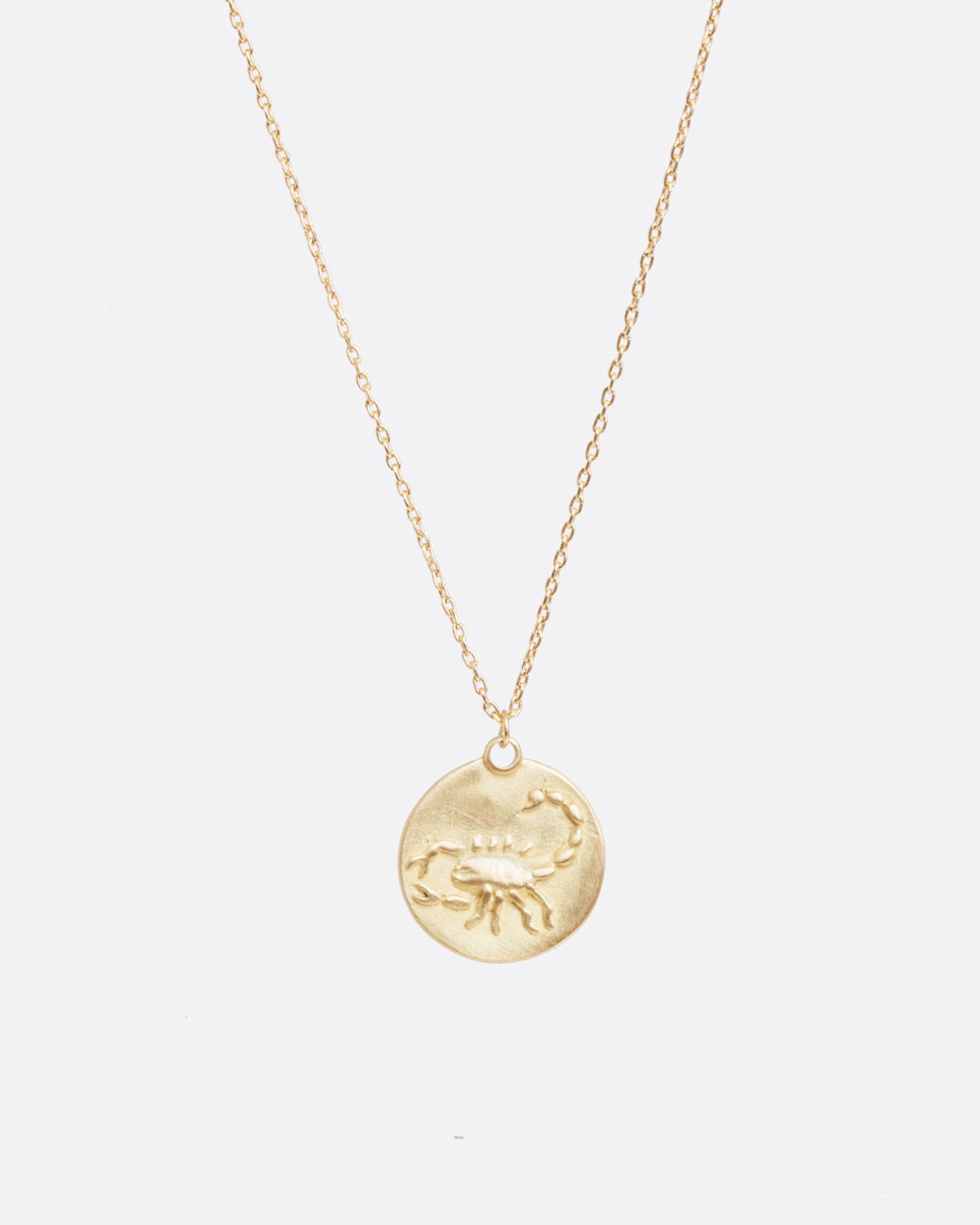 A yellow gold necklace with a round pendant with your choice of zodiac symbol.