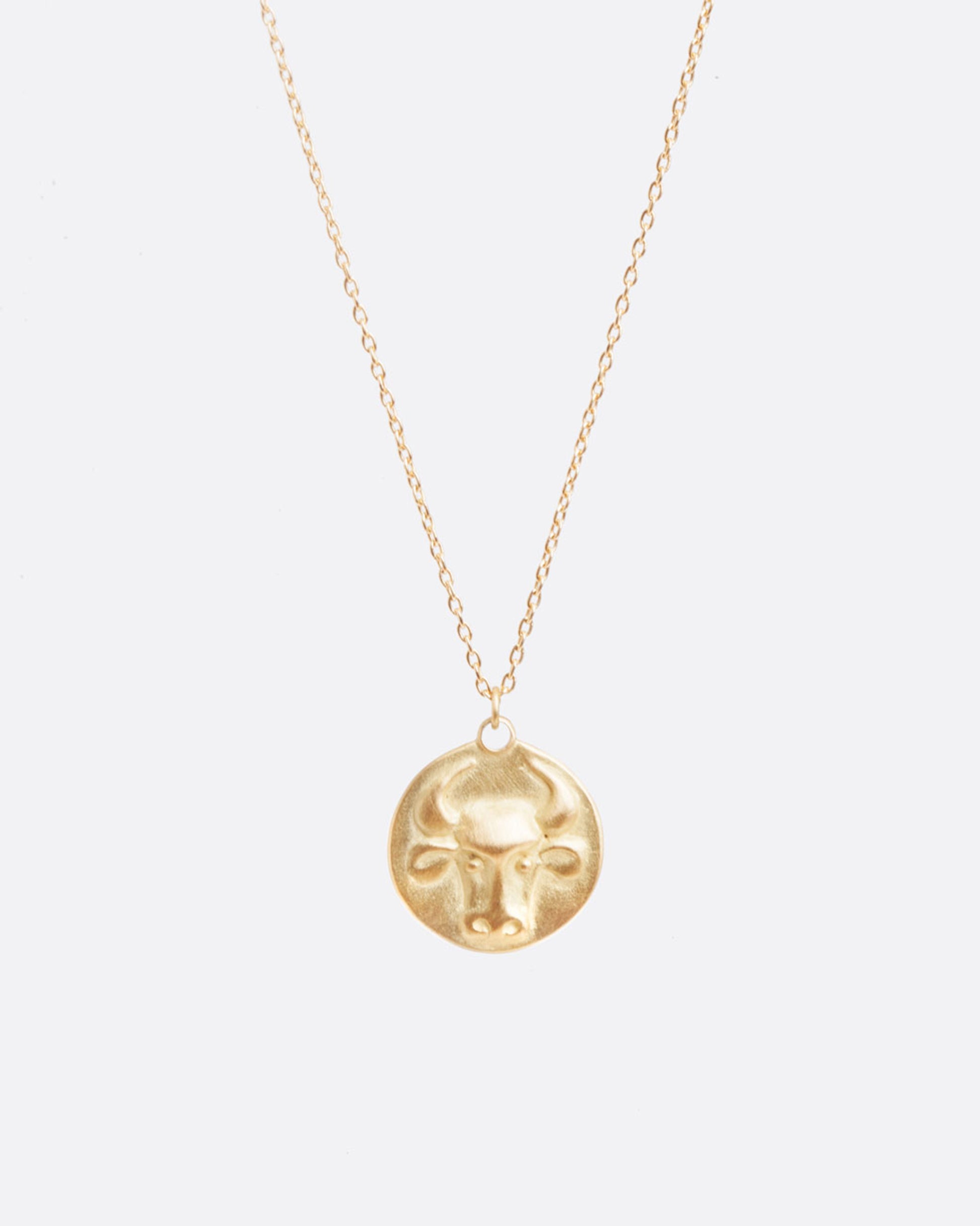 A yellow gold necklace with a round pendant with your choice of zodiac symbol.