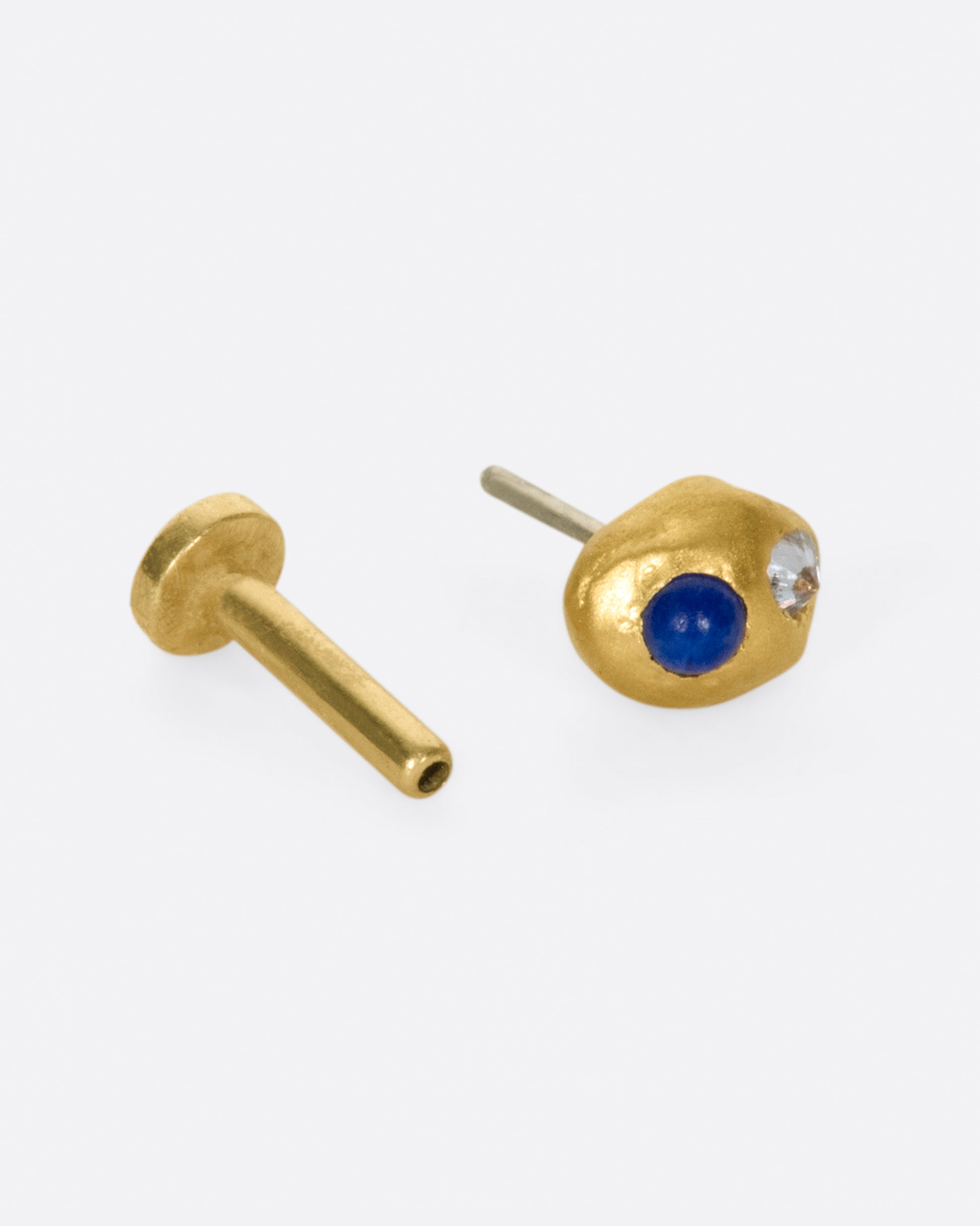 A high karat gold blob threadless earring with one lapis cabochon and one reverse-set white diamond. Shown with a backing.