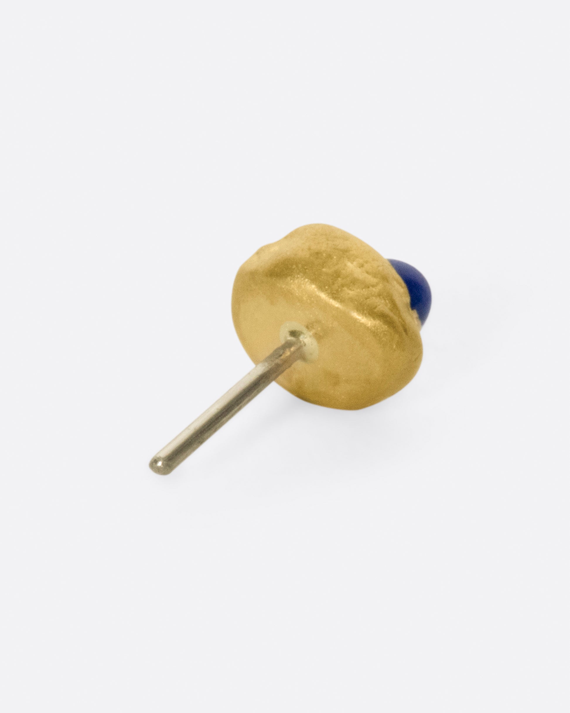 A high karat gold blob threadless earring with one lapis cabochon and one reverse-set white diamond. Shown from the side.