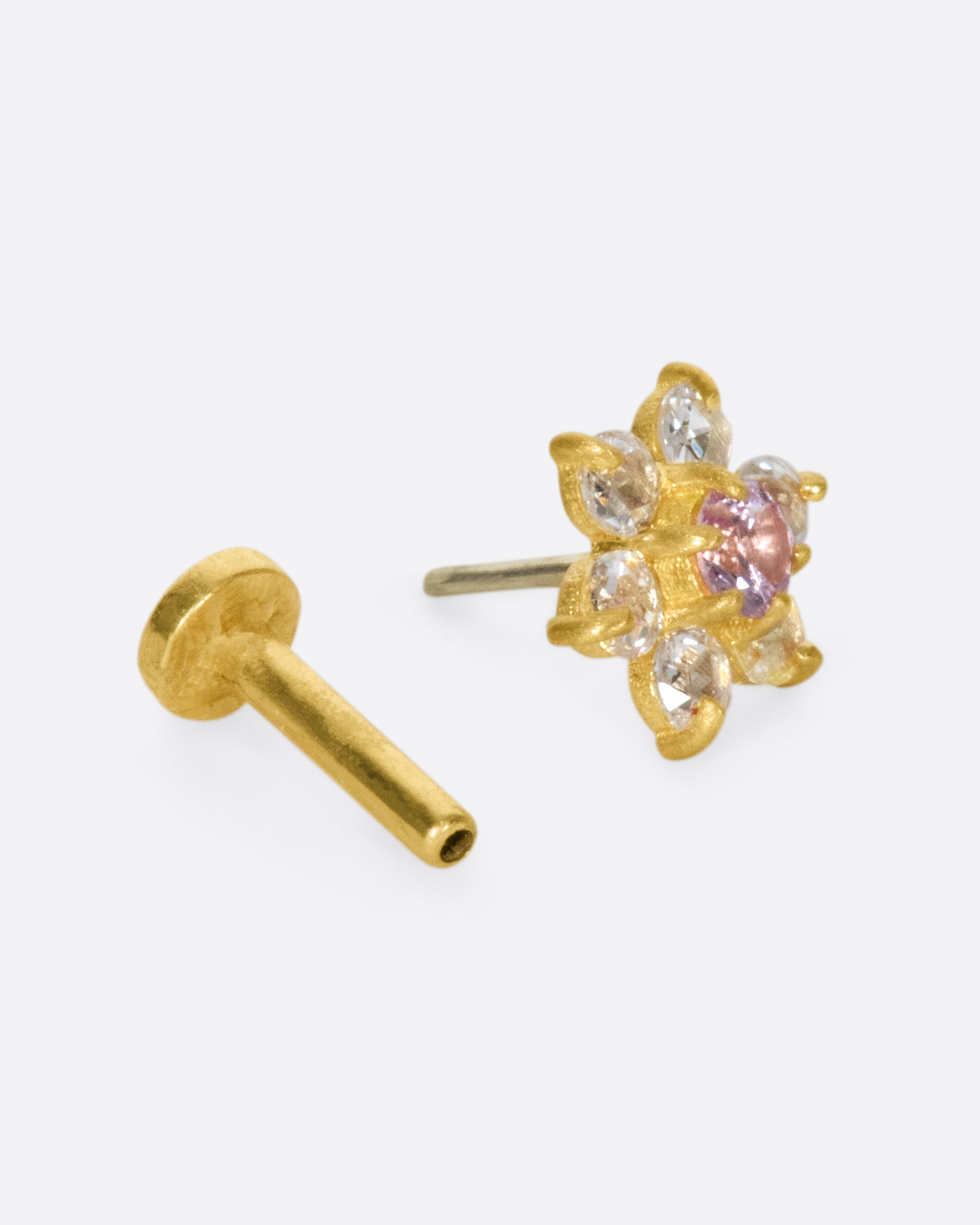 A yellow gold threadless earring front made from 6 white diamond and one pink sapphire in the shape of a flower. Shown with a backing.