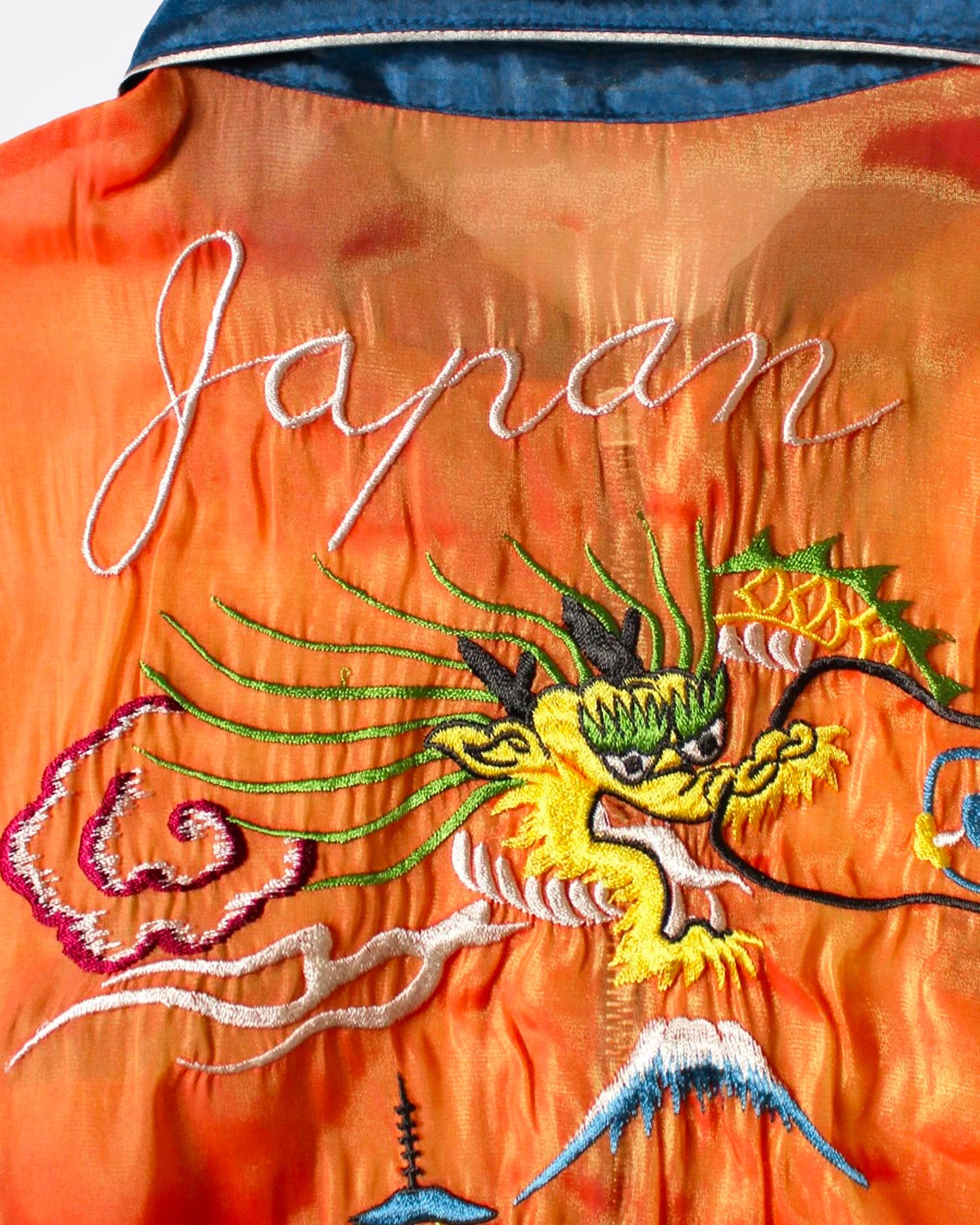 A close up of an orange and blue sheer bomber jacket with dragon embroidery, shown from the back.