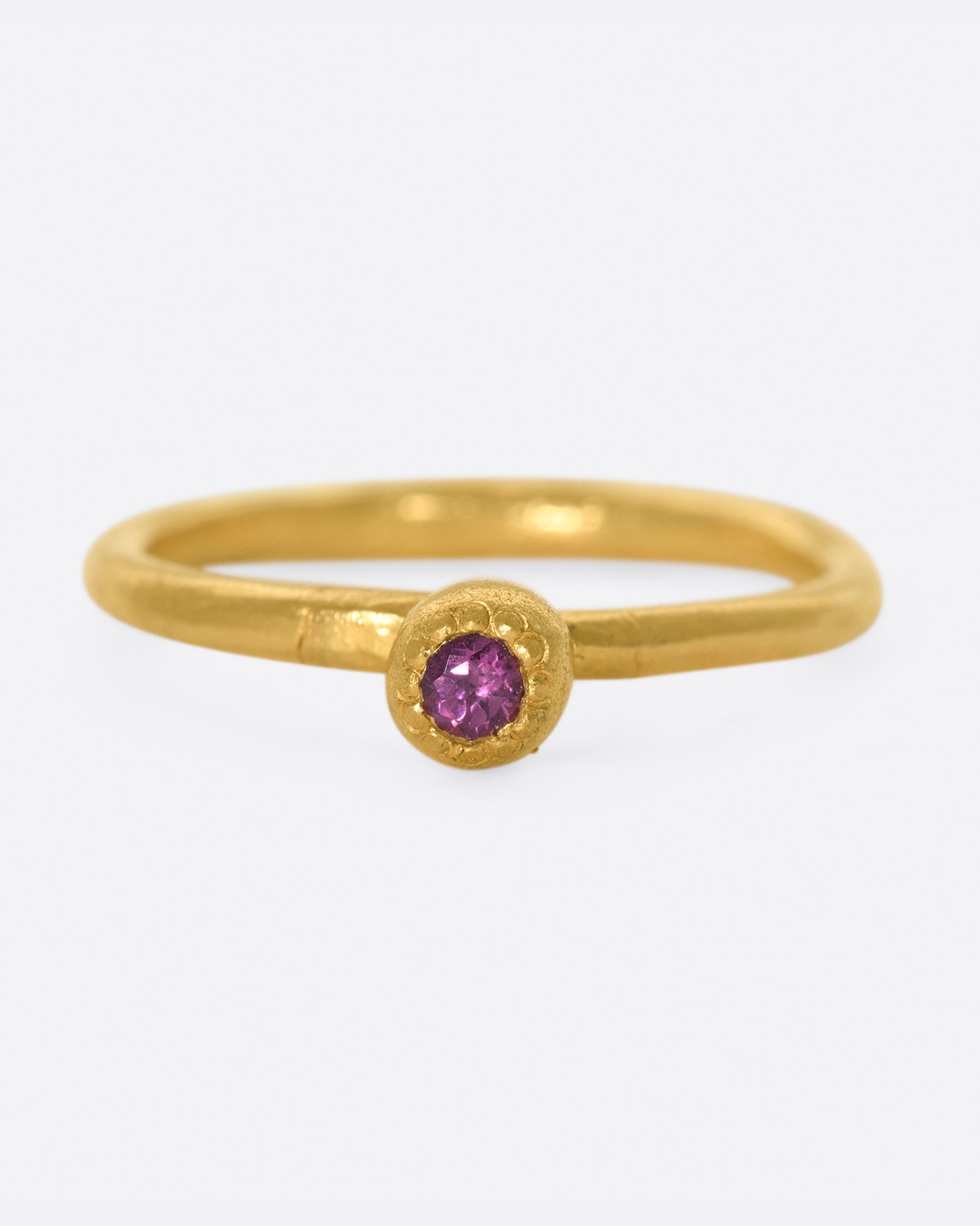 A high karat gold solitaire ring with a rosy pink tourmaline at its center.