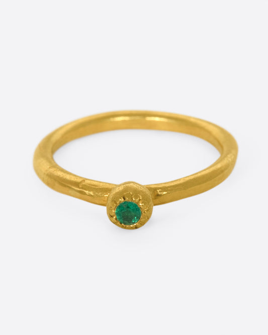 A hand sculpted, high karat gold, solitaire ring with an emerald at its center.