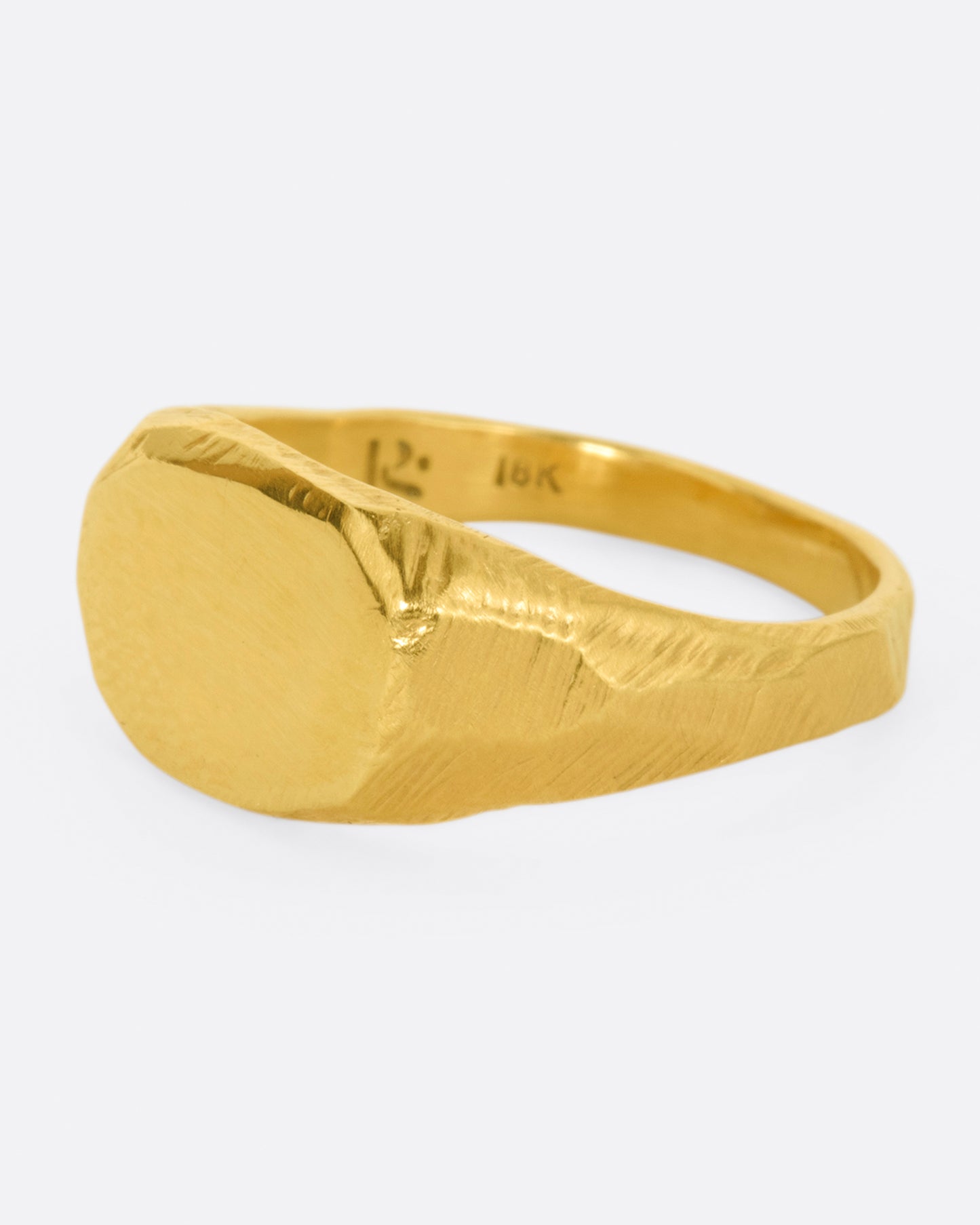 A yellow gold signet ring with a flat, polished face and textured band.