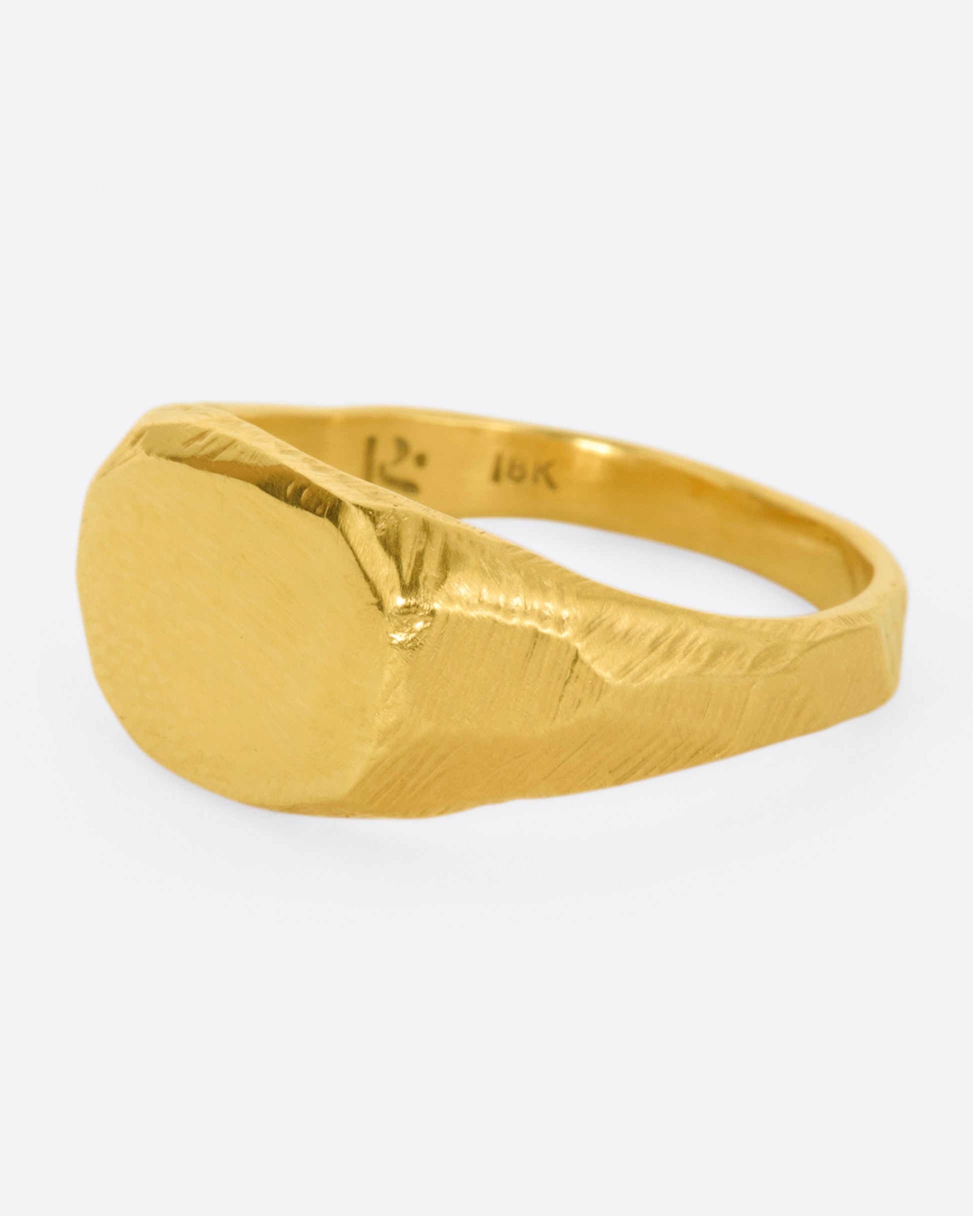 A yellow gold signet ring with a flat, polished face and textured band.