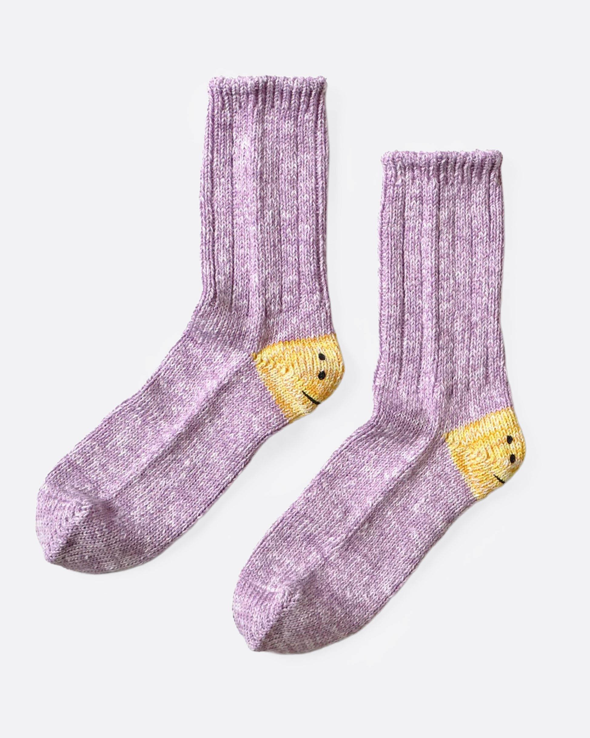 A pair of purple ribbed cotton socks with double-eyed smiley faces on each heel, shown from the side.