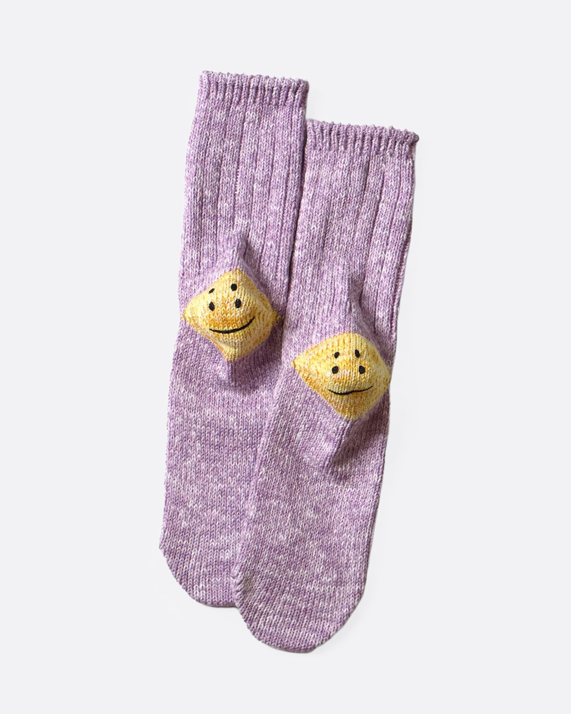 A pair of purple ribbed cotton socks with double-eyed smiley faces on each heel, shown from the bottom.