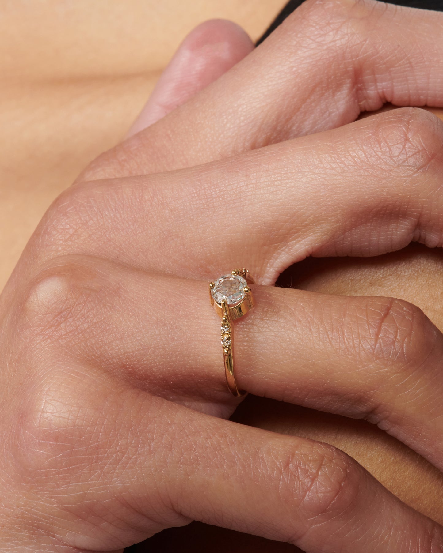 A pale champagne rose cut diamond set in four prongs with two accent diamonds on either side.