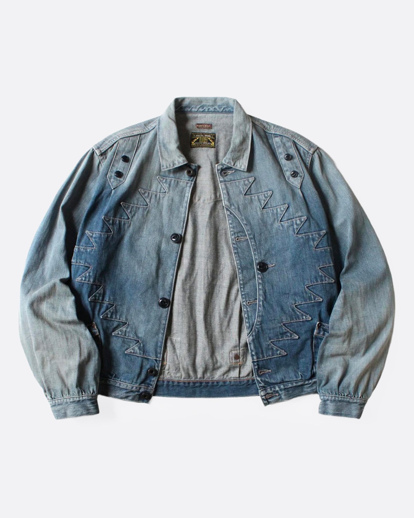 A light blue denim jacket with Chimayo-inspired embroidery across the chest and at each elbow, button closures, and functional back cinch. Shown from the front.