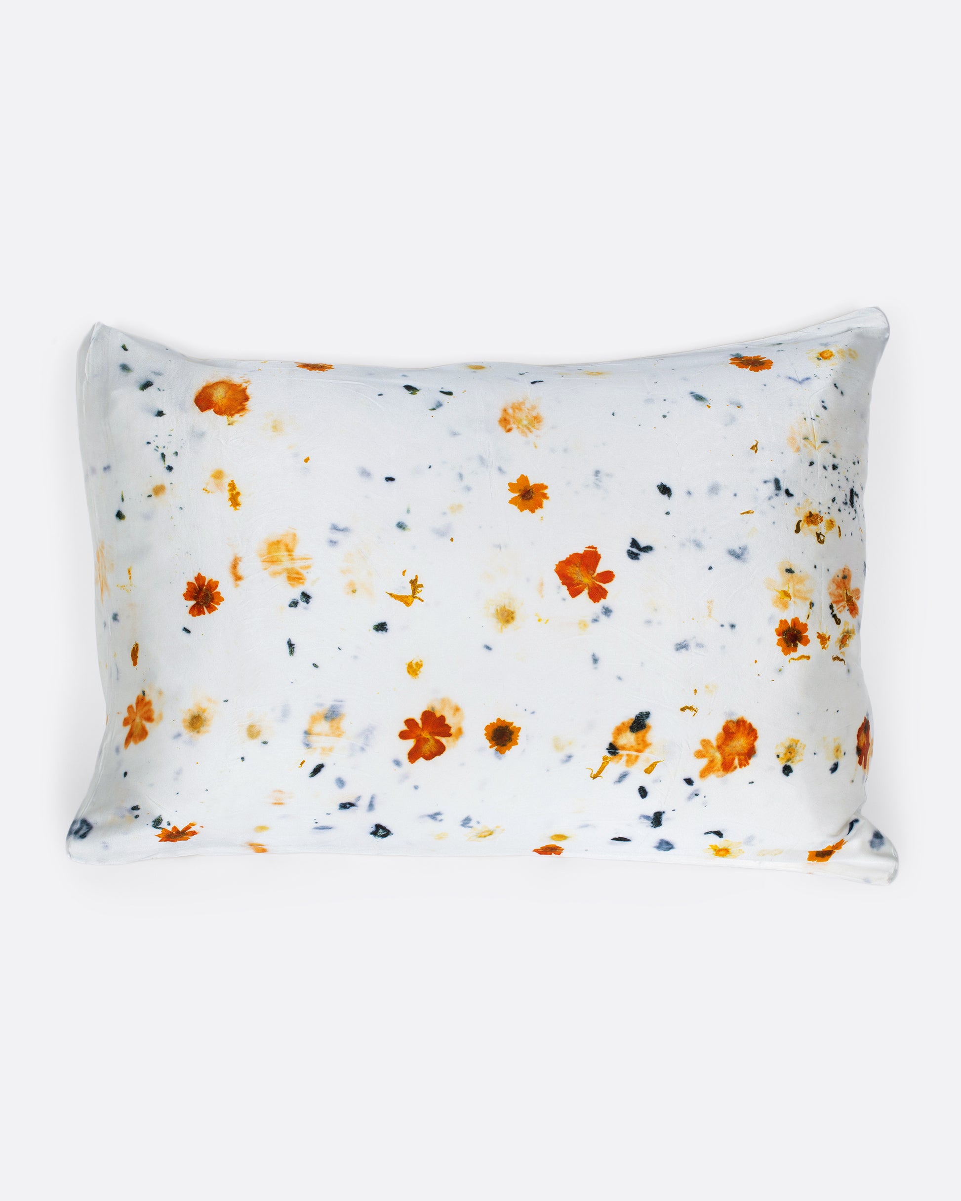 A pillow shown with a yellow and orange flower dotted silk pillowcase.