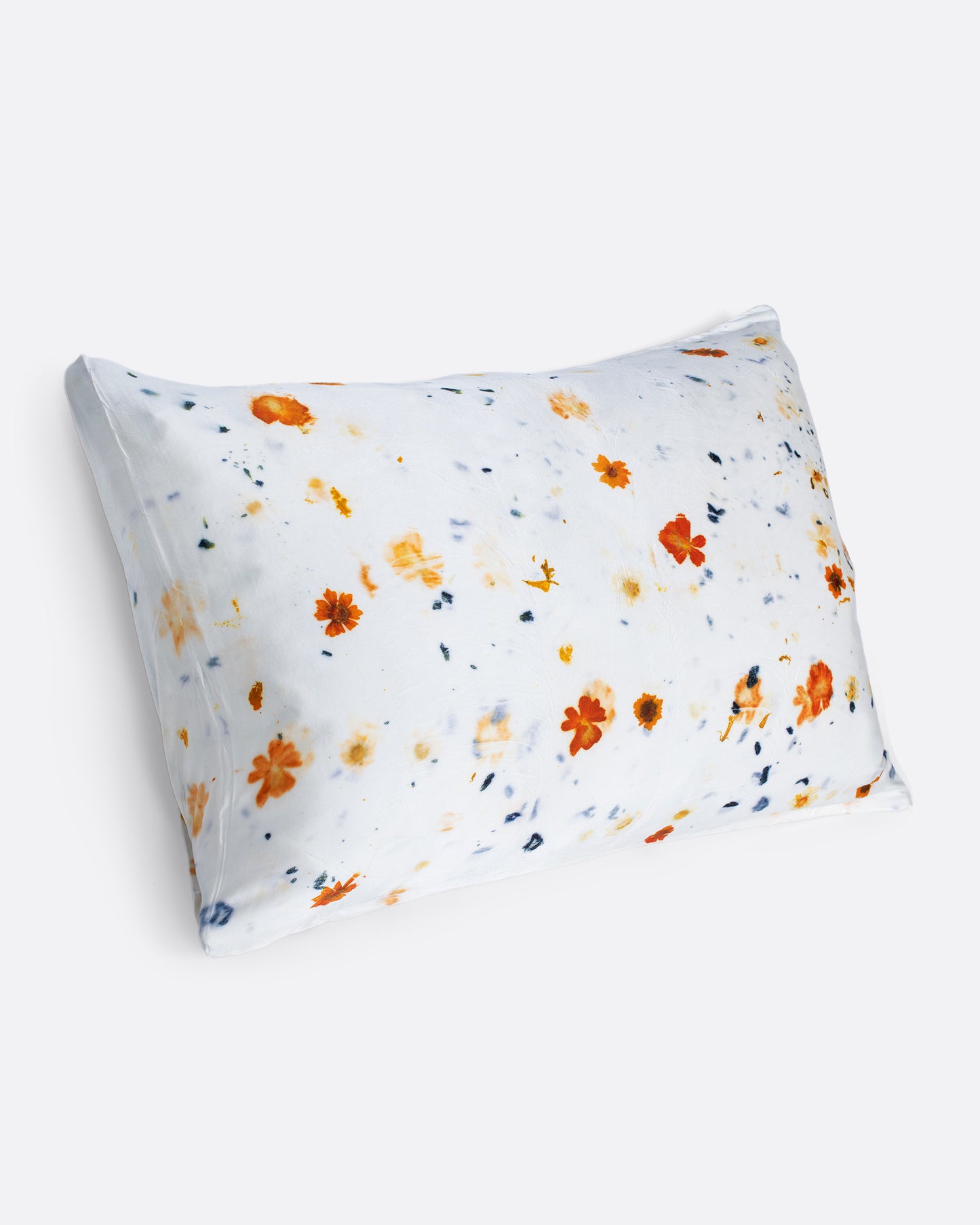 A pillow shown with a yellow and orange flower dotted silk pillowcase.