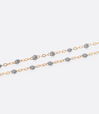 A close up view of a yellow gold cable chain bracelet with silver resin droplets. 