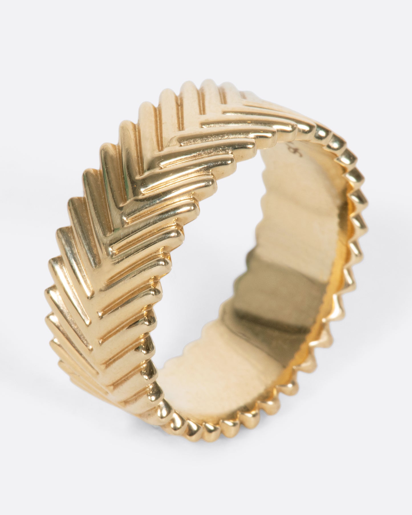 A yellow gold band ring with a braid-like texture, by Selin Kent.