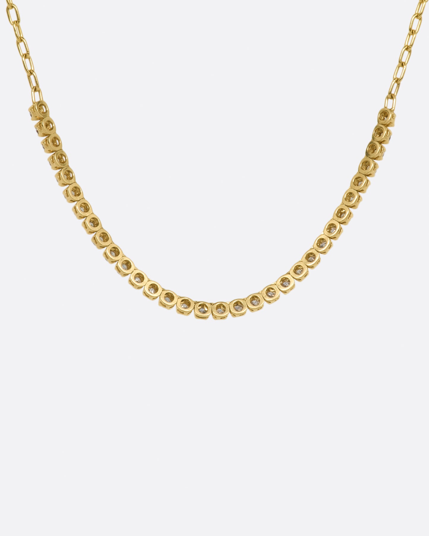 A yellow gold chain necklace with a section of green, champagne and cognac diamonds along the front. Shown from the back.