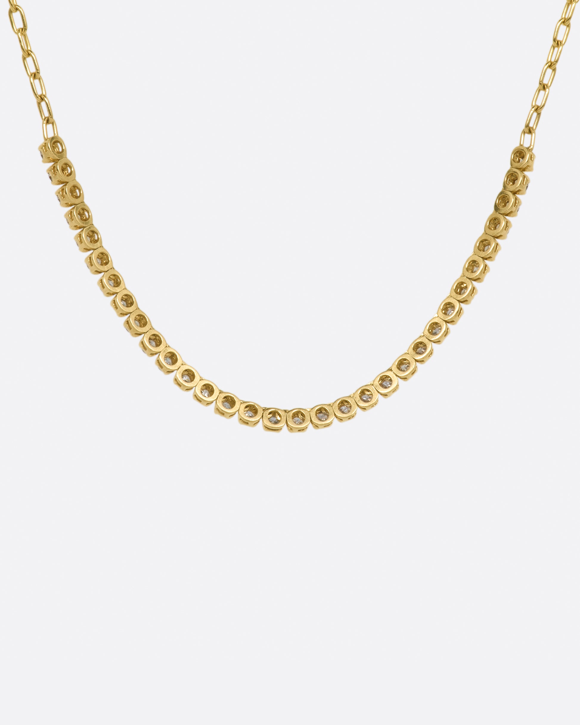 A yellow gold chain necklace with a section of green, champagne and cognac diamonds along the front. Shown from the back.