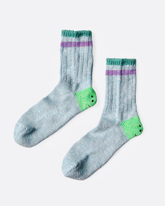 A pair of blue socks with green smiley heels, and green and purple stripes on each ankle. Shown from the side.
