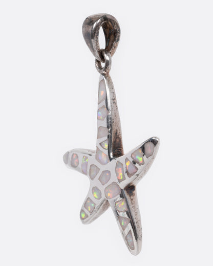 A silver starfish pendant with opal inlay show from the side.