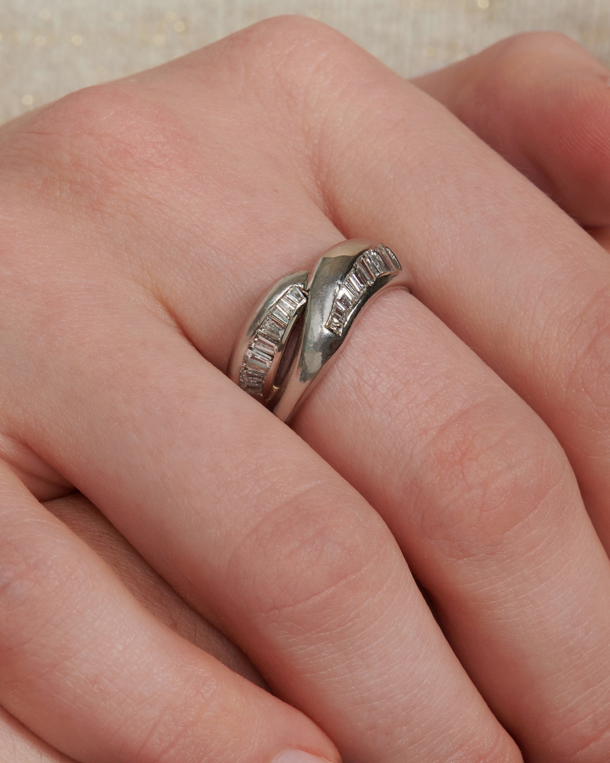 A platinum ring with two arches, lined with baguette diamonds.