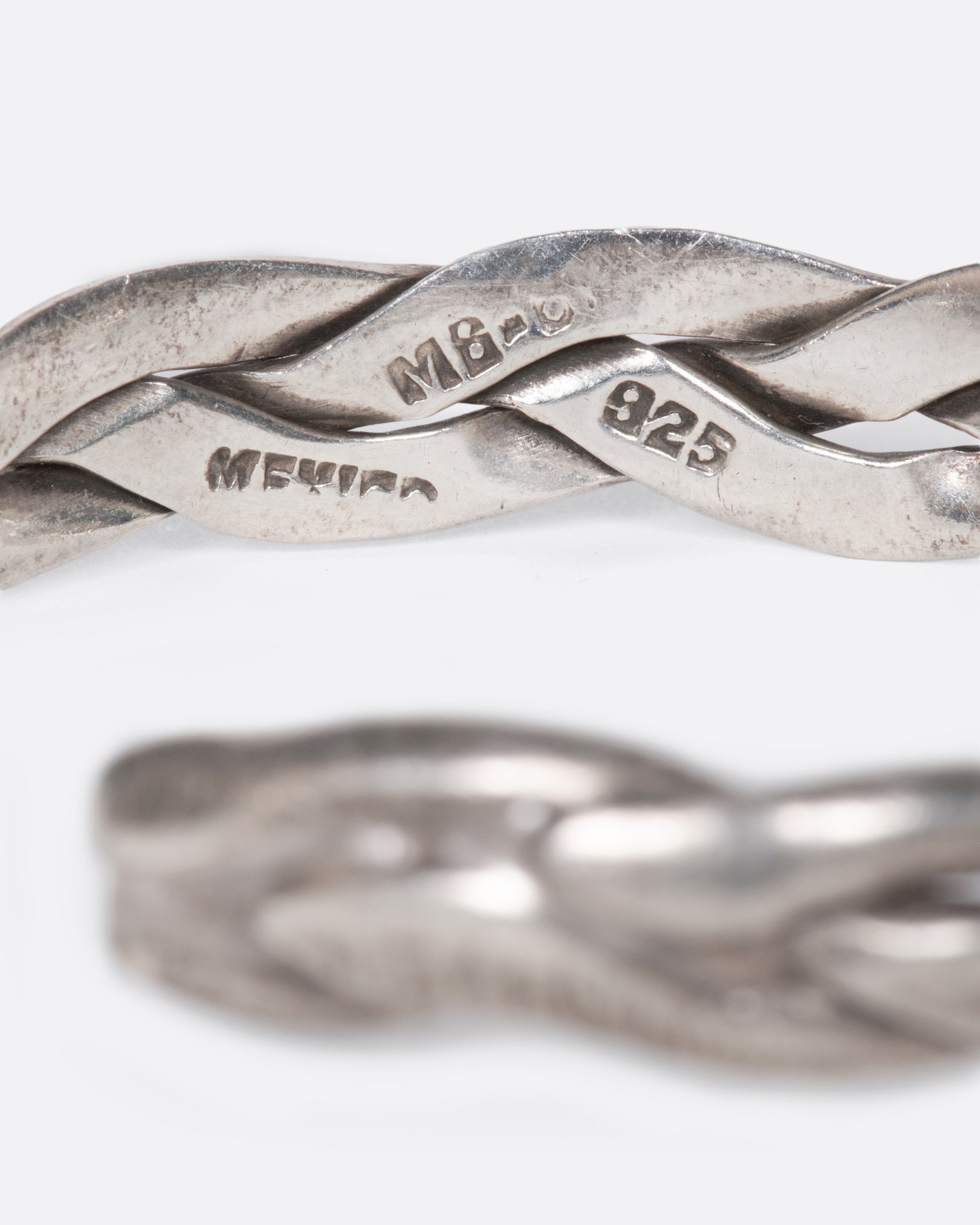 A close up of the hallmarks on a vintage sterling silver cuff bracelet made from three braided strands of silver.