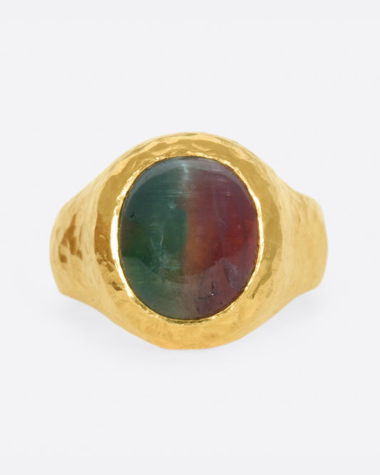 A bicolor pink and green tourmaline sits at the center of this heavy, hammered, high karat gold ring.