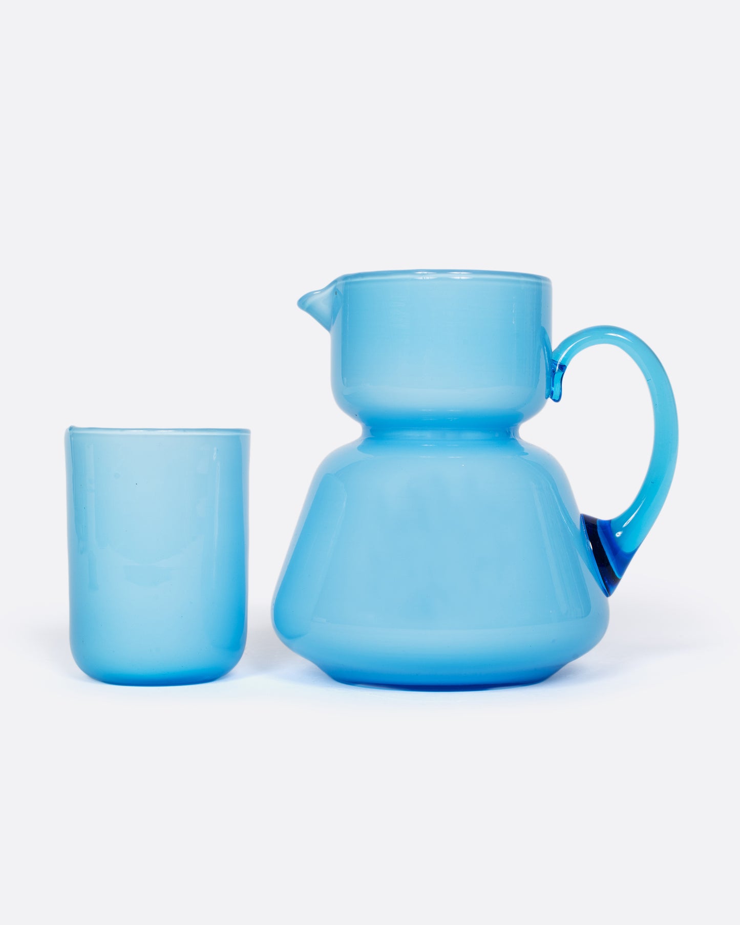 A vintage cased glass cup and creamer with an hourglass shape. Cased glass is made with a layer of white glass underneath creating the velvety, light blue hue.