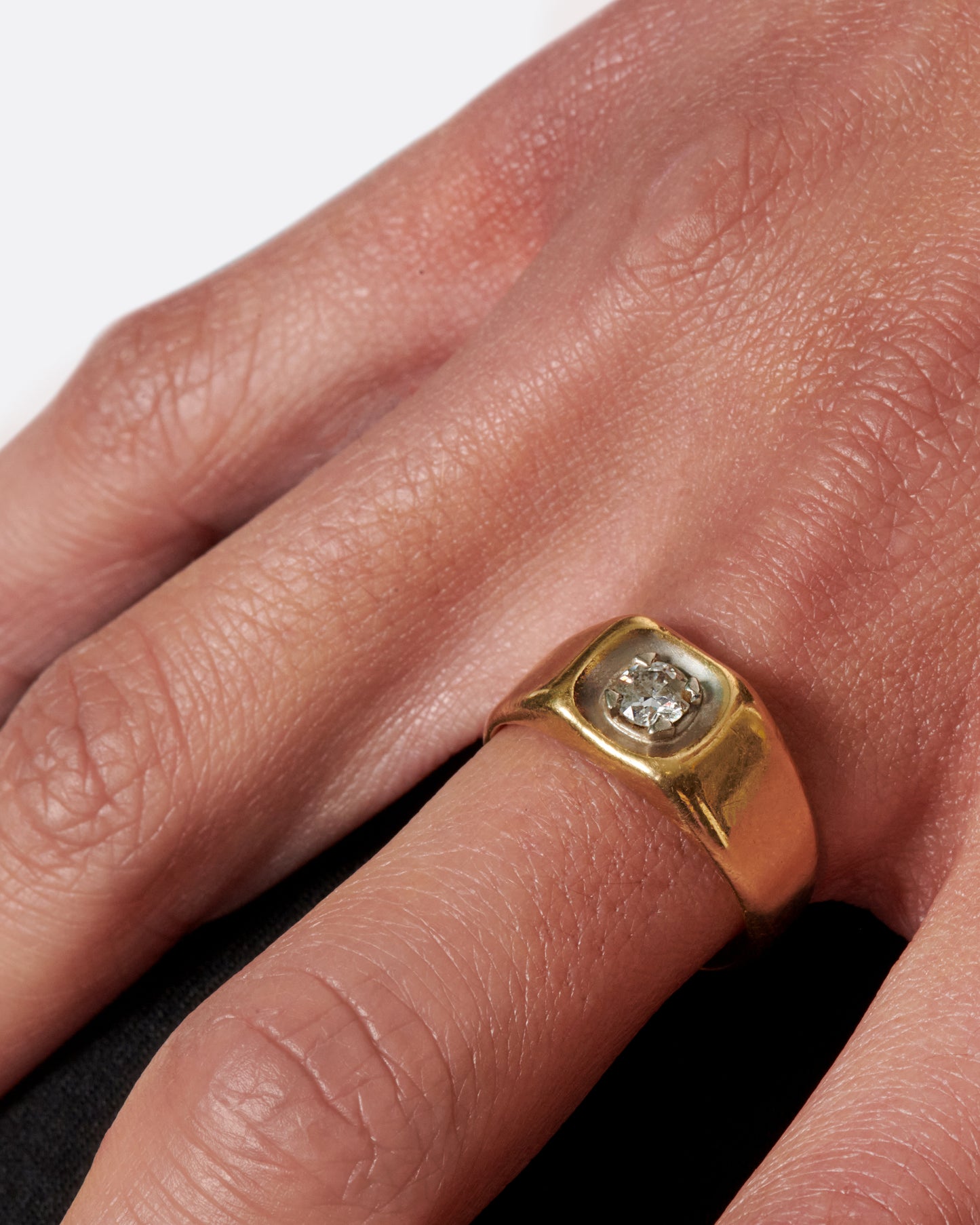 A vintage gold signet ring with a sunken diamond at its center.